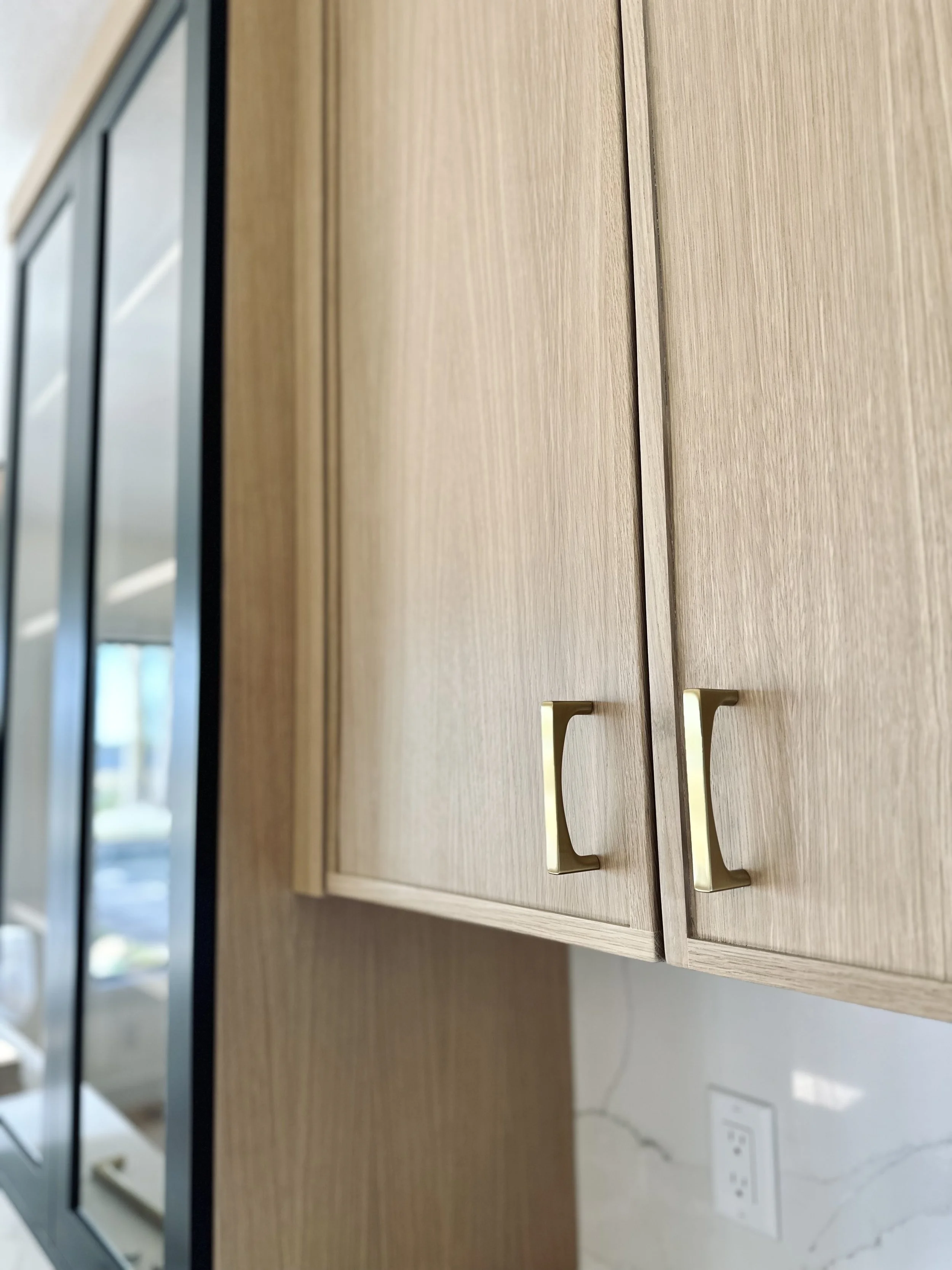 Close-up of wooden cabinet doors with gold handles in a modern kitchen.