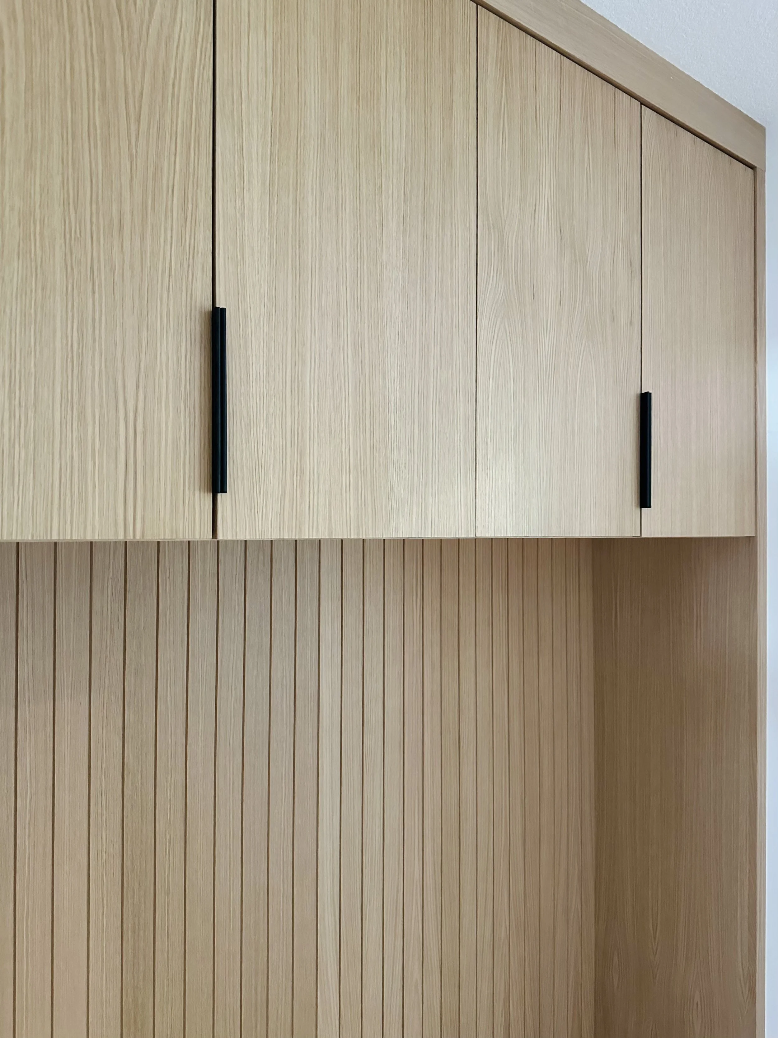 Close-up of a wooden cabinet and wall with vertical wood paneling.