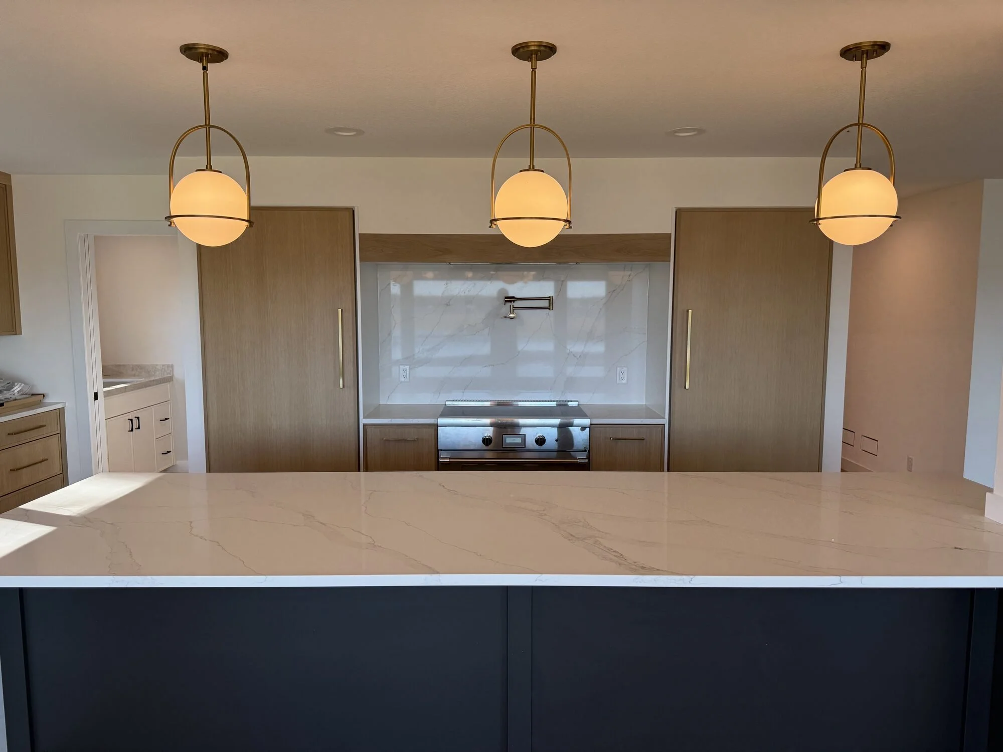 Navy kitchen island with brass pendants and white oak cabinetry, Forest Lake, MN