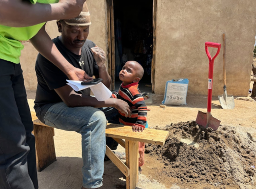 A classroom with a teacher and young children holding red balloons, with a blackboard and alphabet chart in the background.