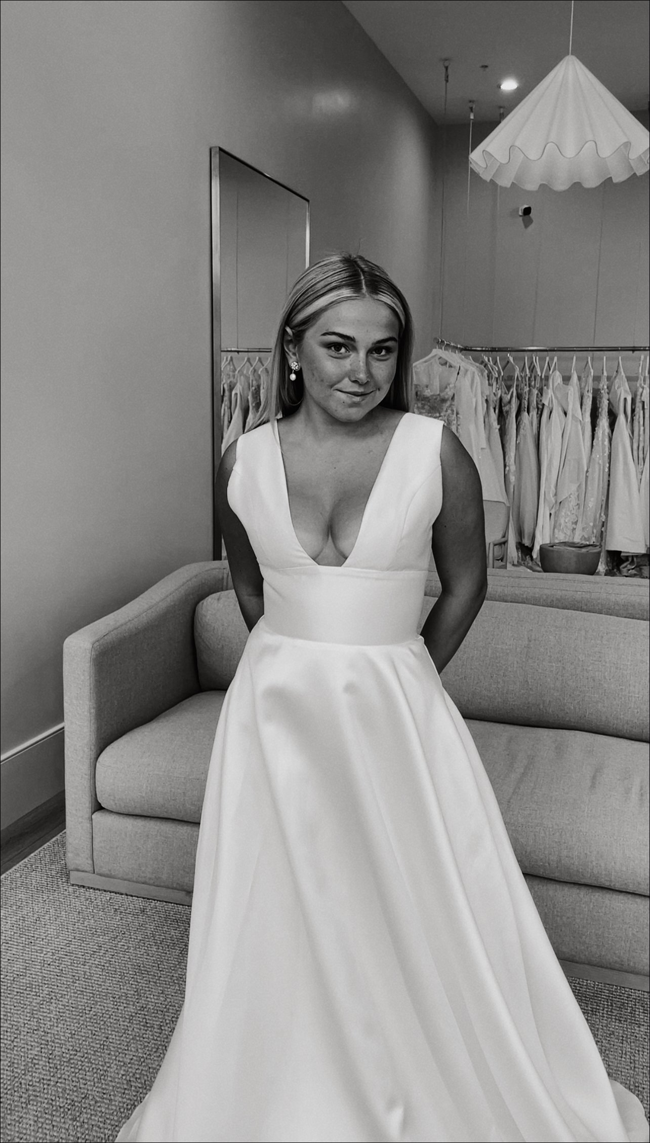 A woman in a wedding dress standing in a bridal boutique.