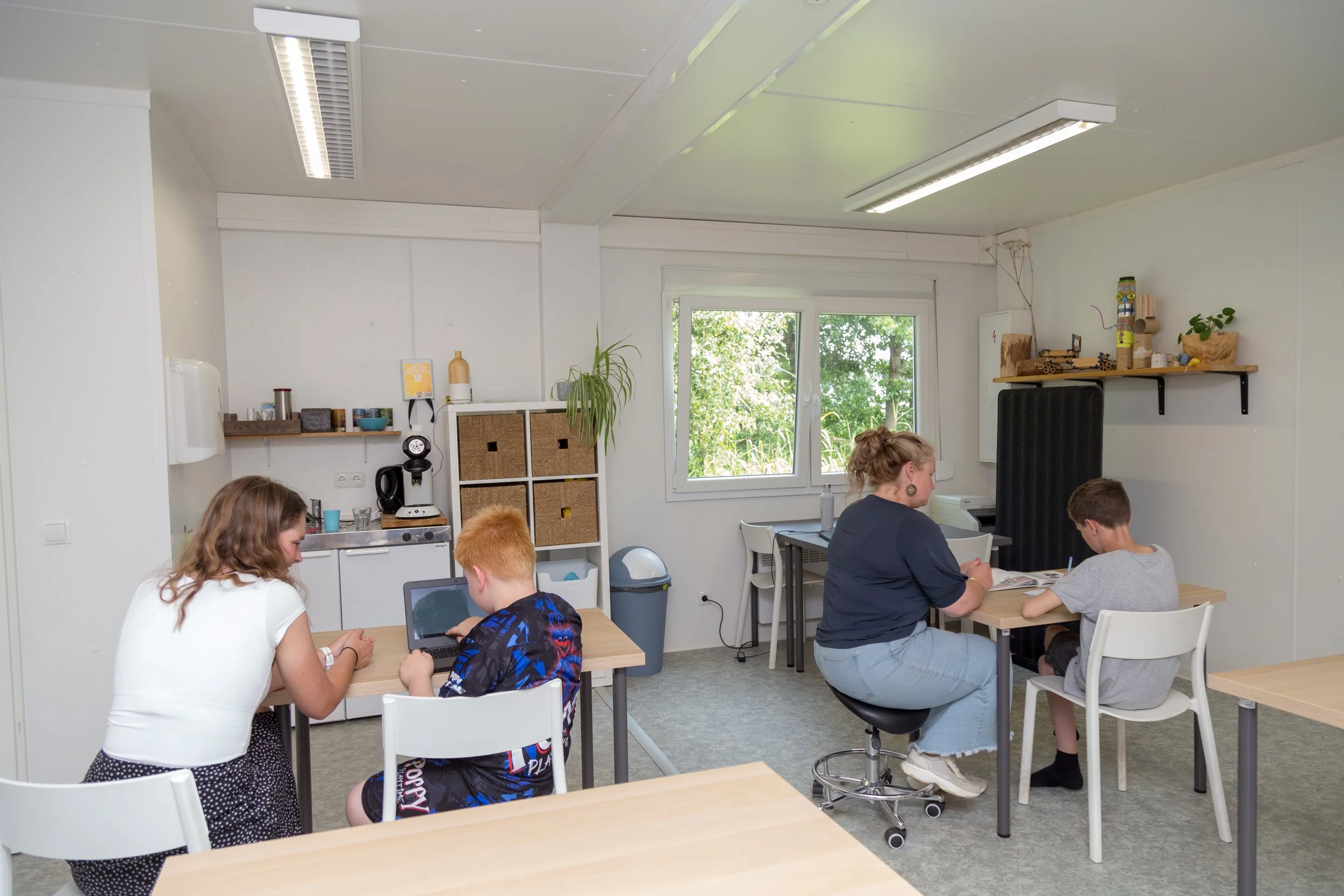Binnenruimte met kinderen en een volwassene die aan tafel zitten van het onderwijs-zorgarrangement (OZA) op maat in Terhole van Binnenste Buiten Zorgboerderij