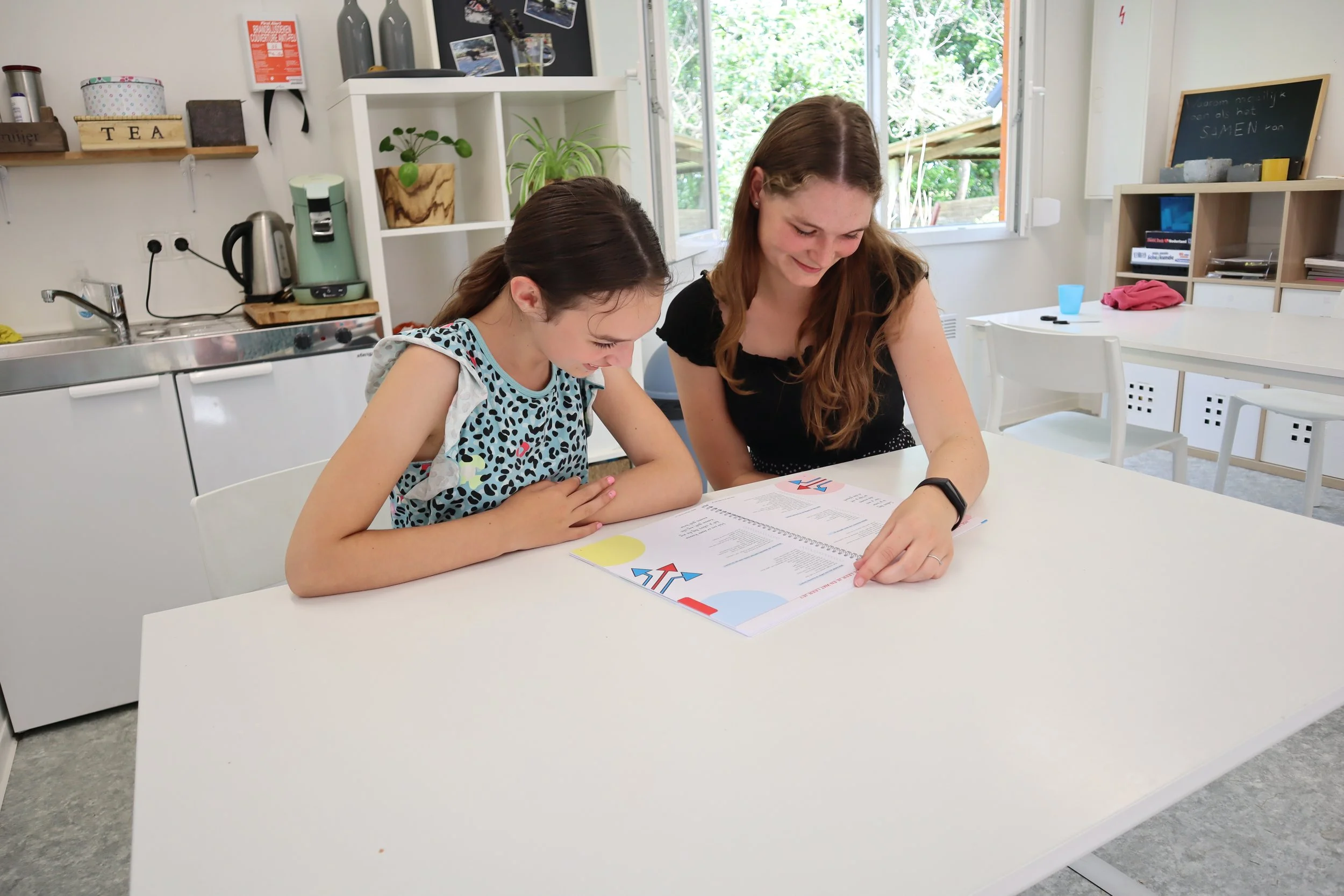 Begeleider en  leerling kijken samen naar een open boek van het onderwijs-zorgarrangement (OZA) op maat in Terhole van Binnenste Buiten Zorgboerderij