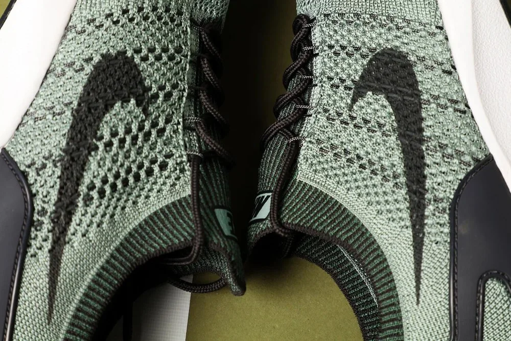 Close-up of a pair of Nike athletic shoes with green knit uppers and black Nike swoosh logos.