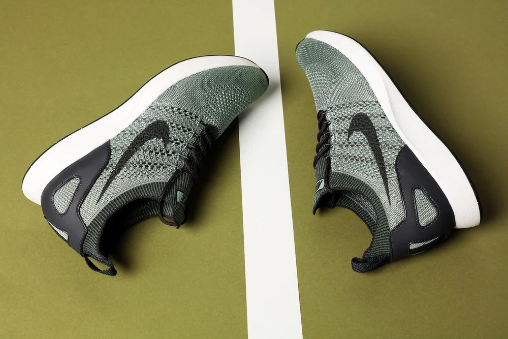 A pair of Nike running shoes on a green surface with a white stripe in the middle.