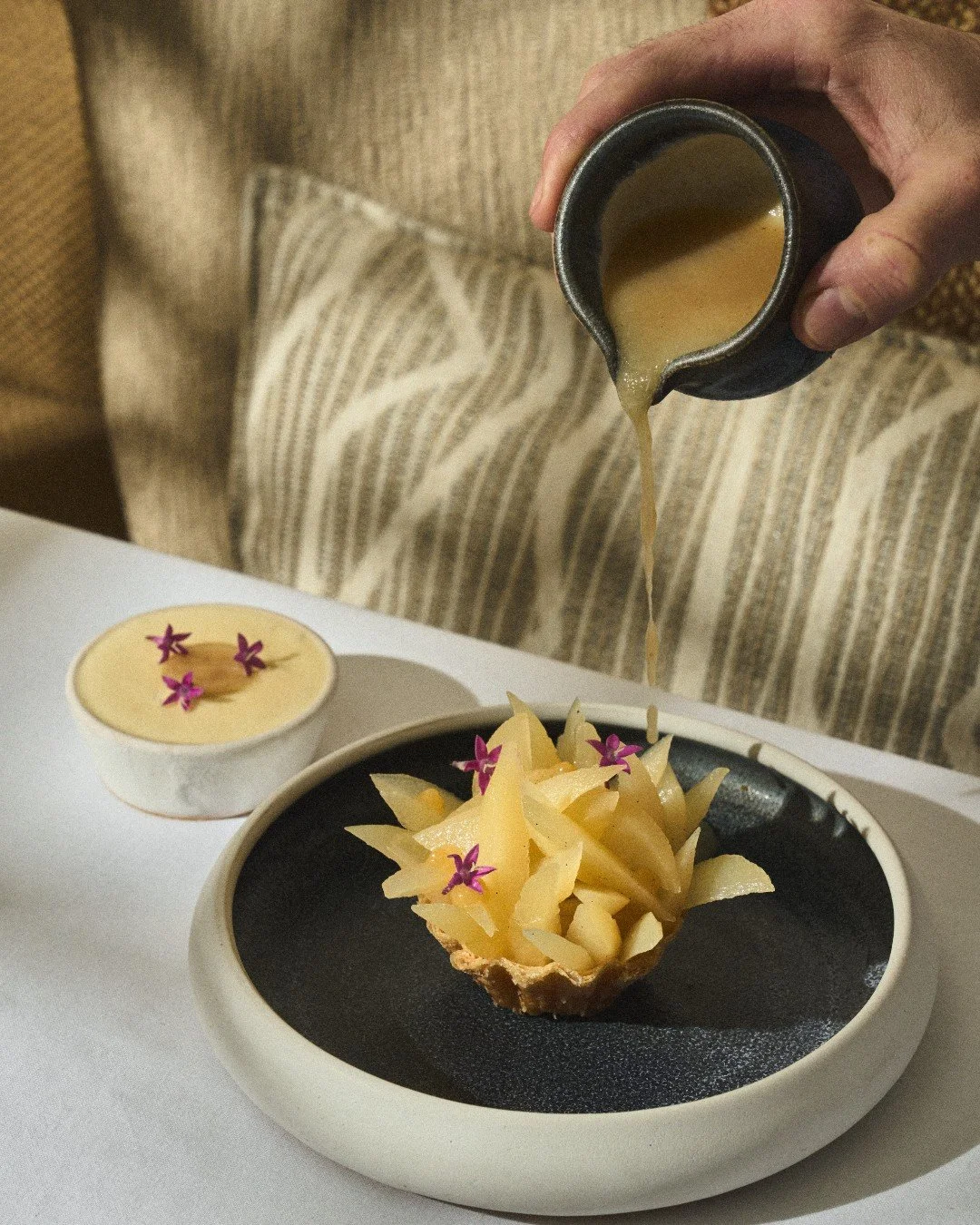 A sweet finale inspired by the Mediterranean.✨ Our Greek Custard Pie features buttery, golden ph&iacute;llo with ripe pear and herb-kissed custard, paired with a scoop of honey ice cream for a perfectly balanced finish. Reserve your sweet escape to A