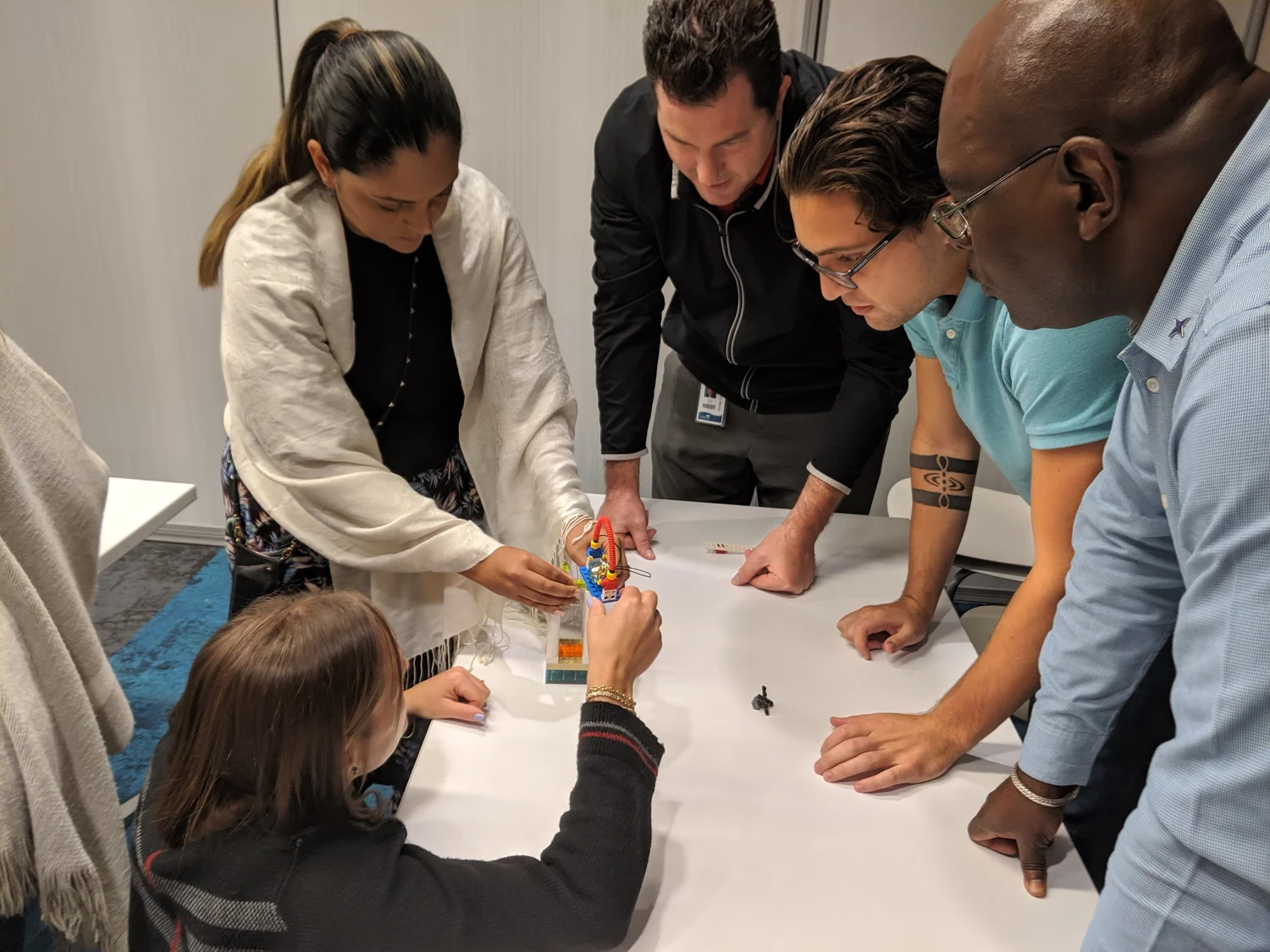 Participants leaning over a table, building and pointing at LEGO models
