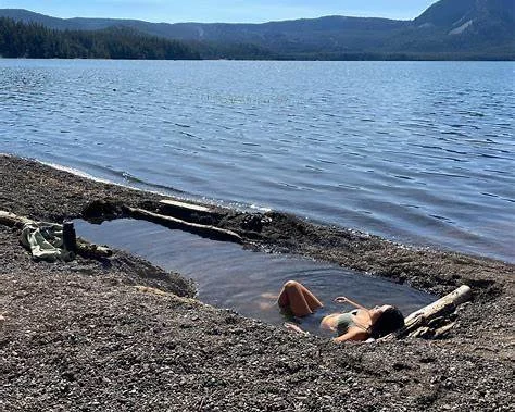 Woman soaking in natural hot springs by Paulina Lake near Bend, Oregon.