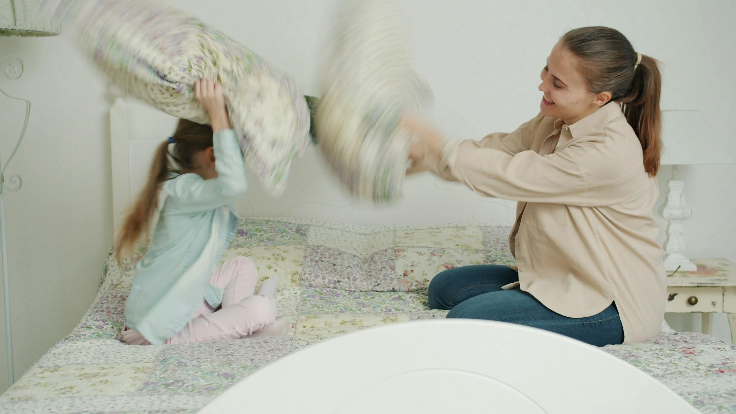 a nanny and child play inside an Indian hill Ohio home pillow fighting on the bed