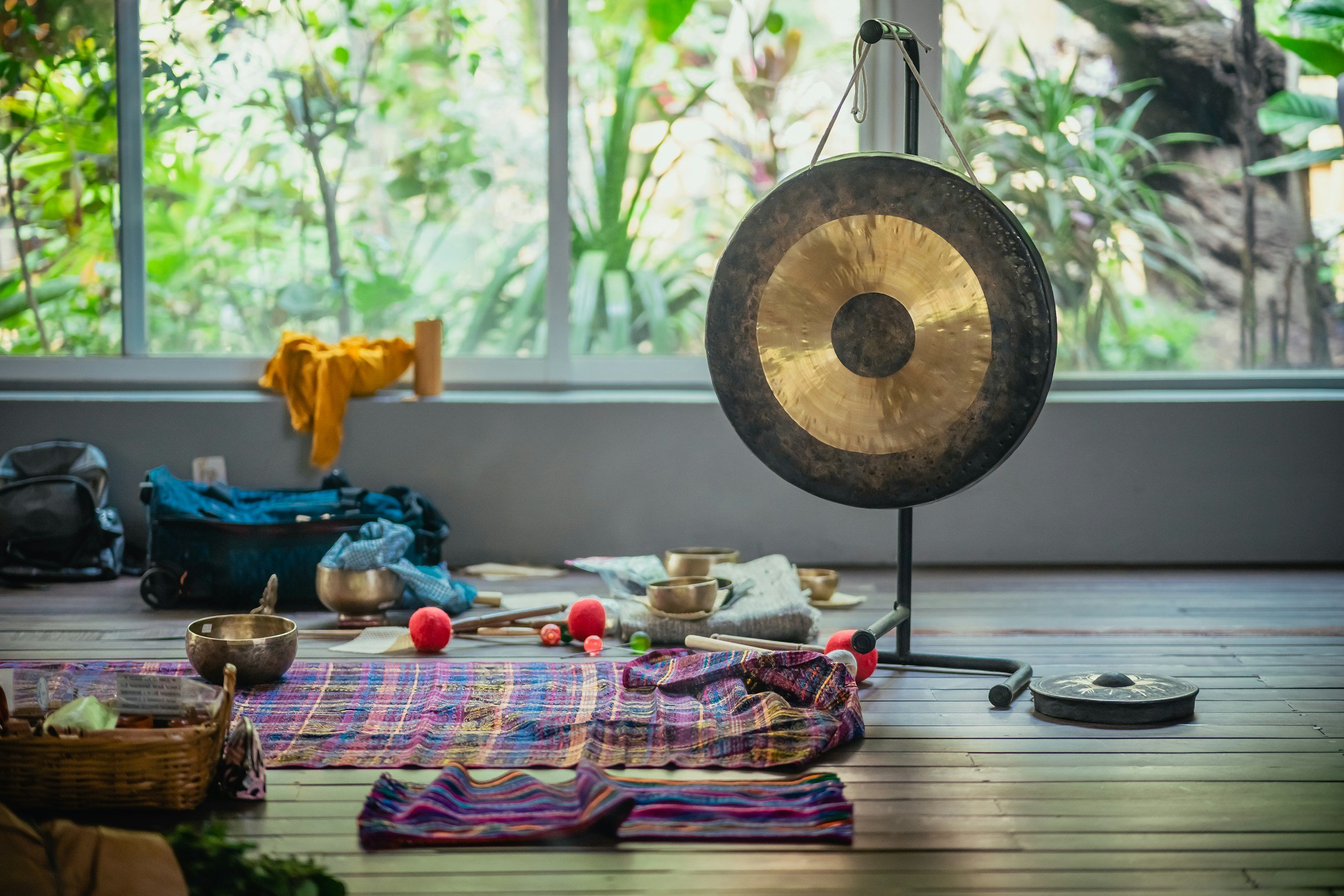 A gong in a sound healing studio. There are himalayan bowls, mallets and other healing instruments on the floor.