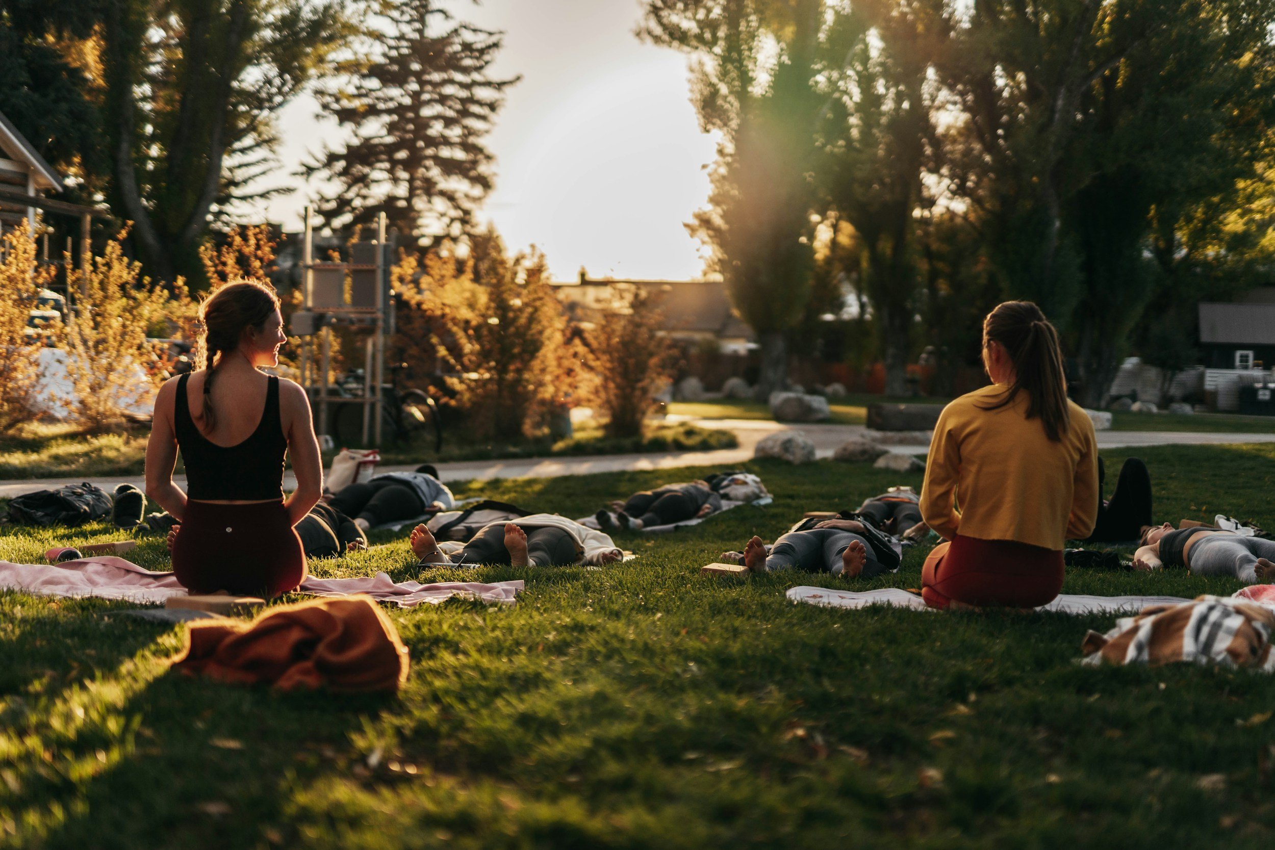 two women teach an outdoor yoga class.