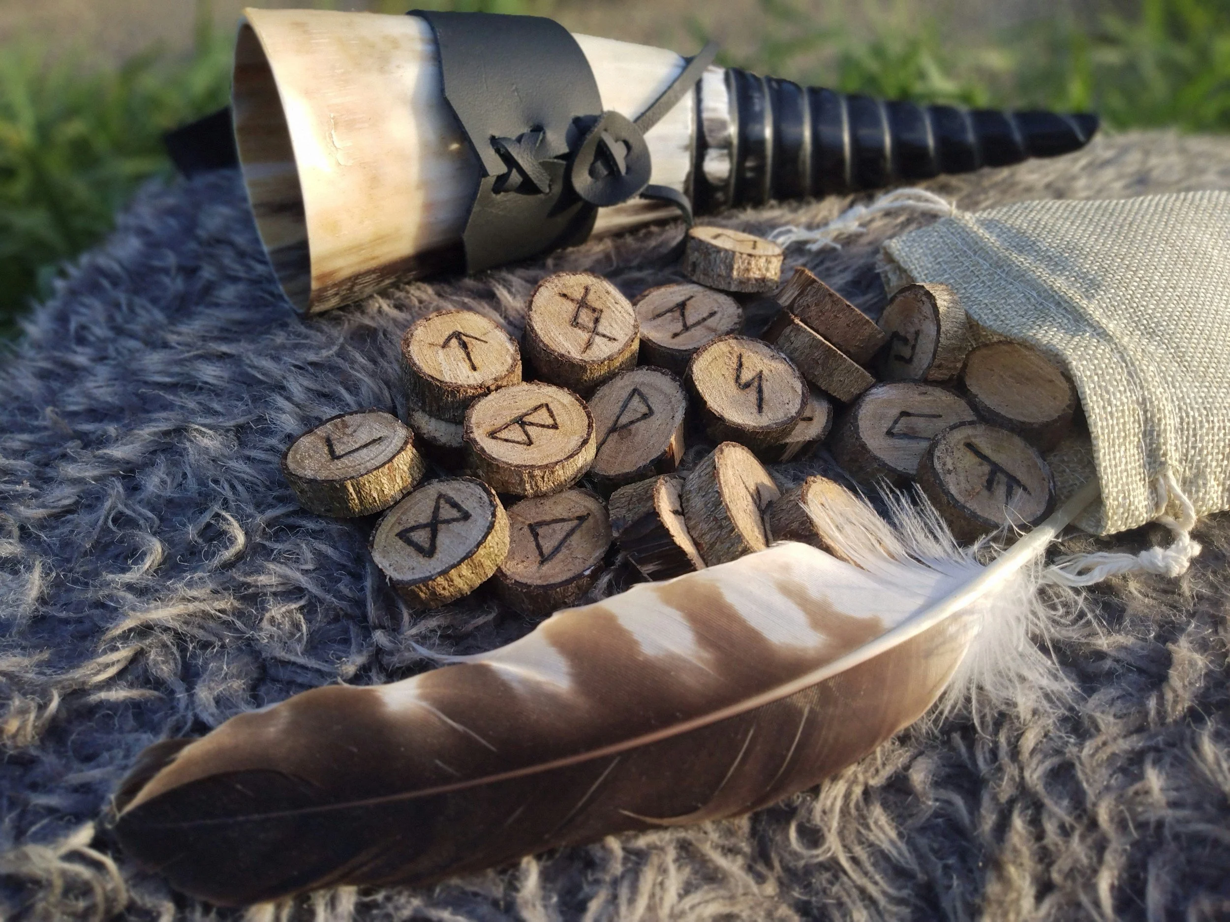 runes, a feather and horn on a sheep skin blanket.