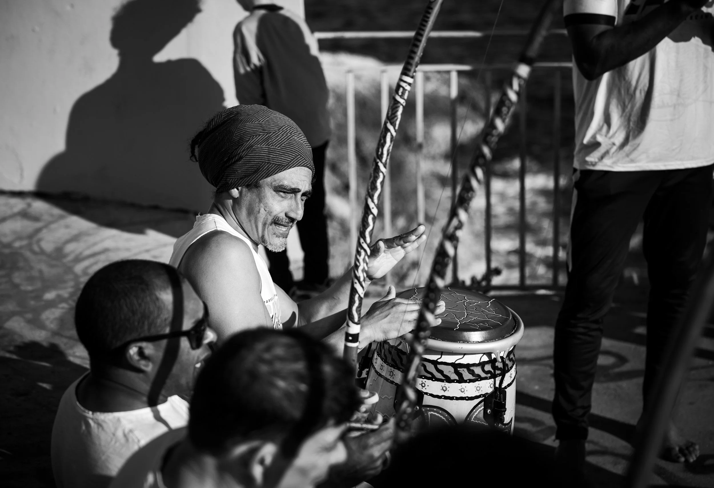 black and white photo of a man drumming with people sitting around him in a semi circle.
