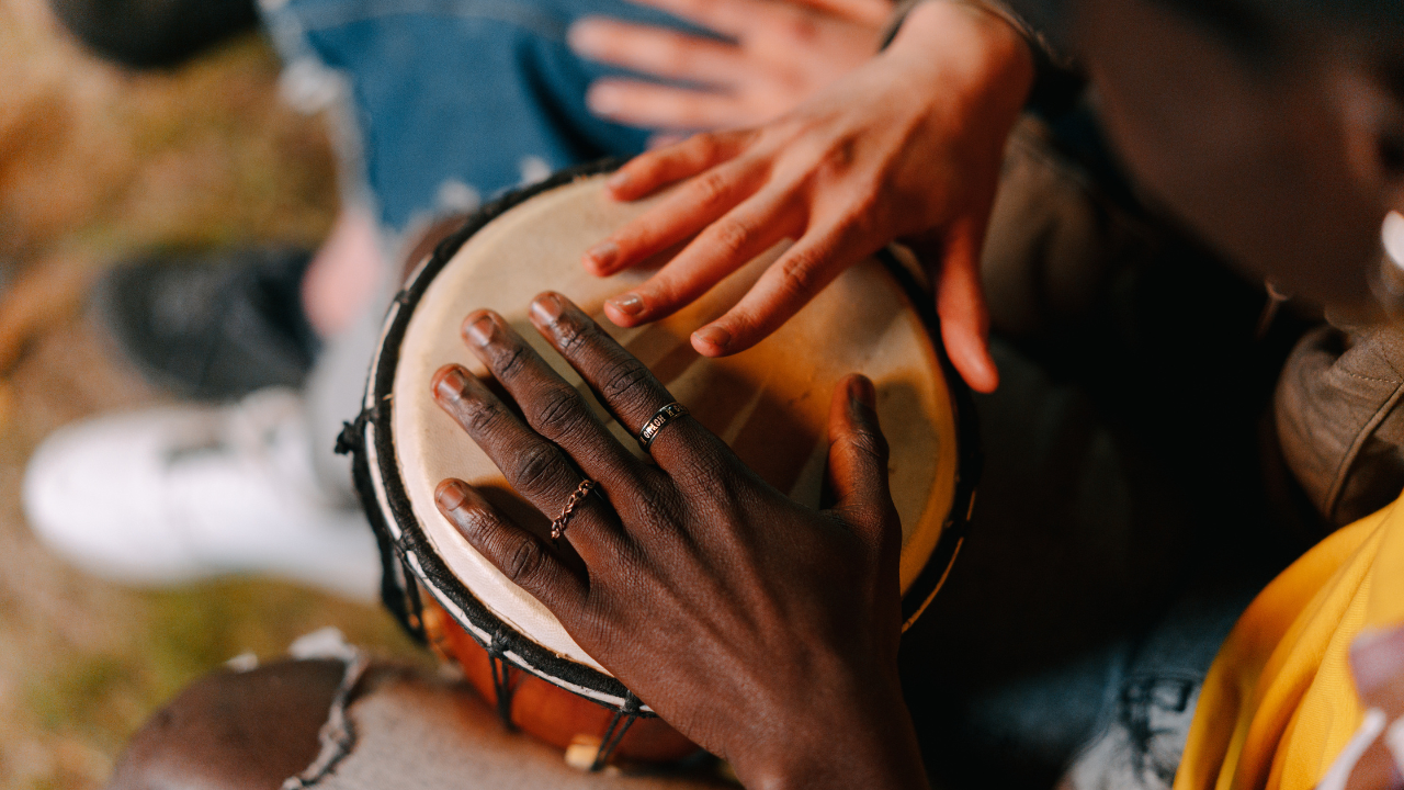 Two people drum on a single instrument.