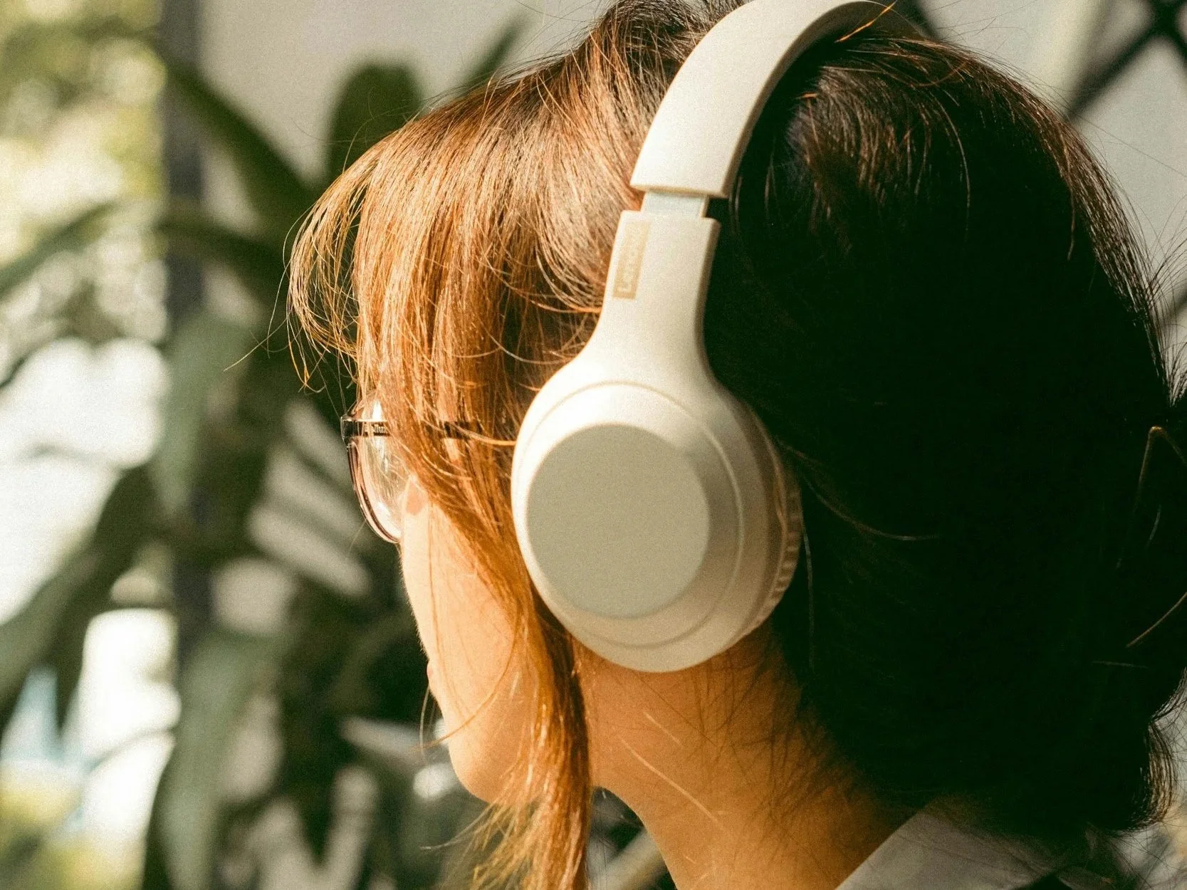 a person listens to music with white over the ear headphones.