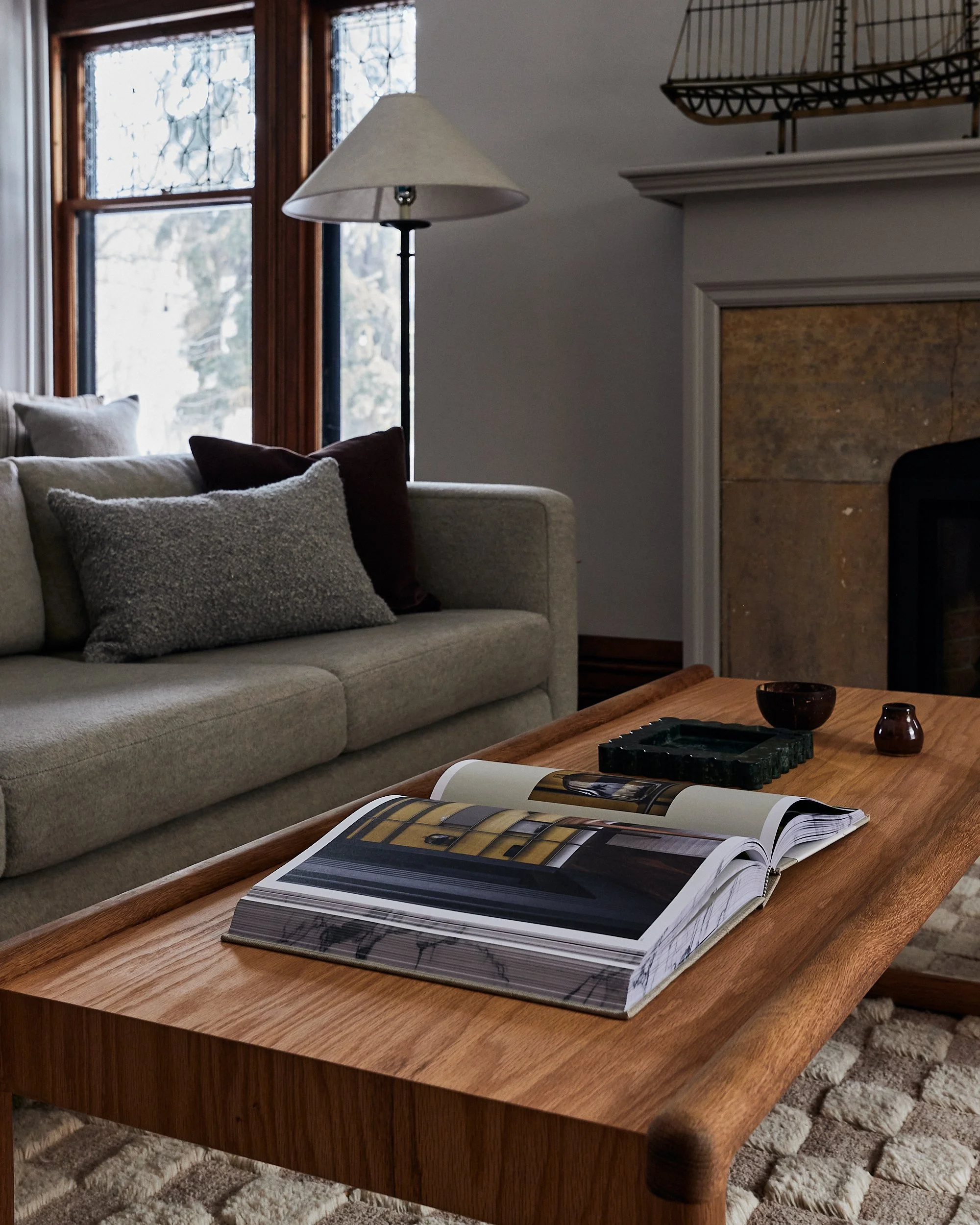An open art book sits on top of a rectangular wooden coffee table in a living room.