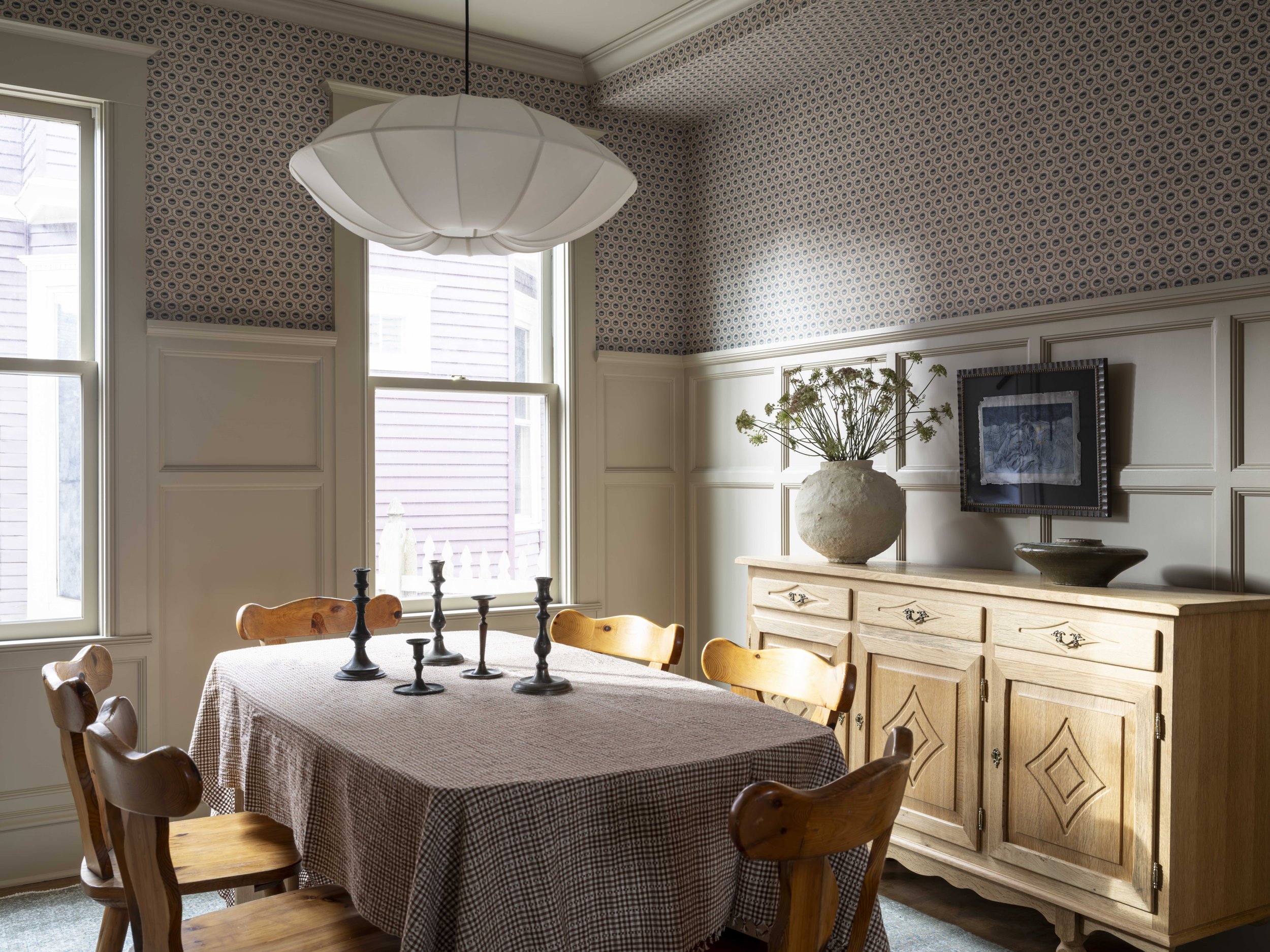 A tight plaid tablecloth covers a dining room table with a vintage sideboard in the background.