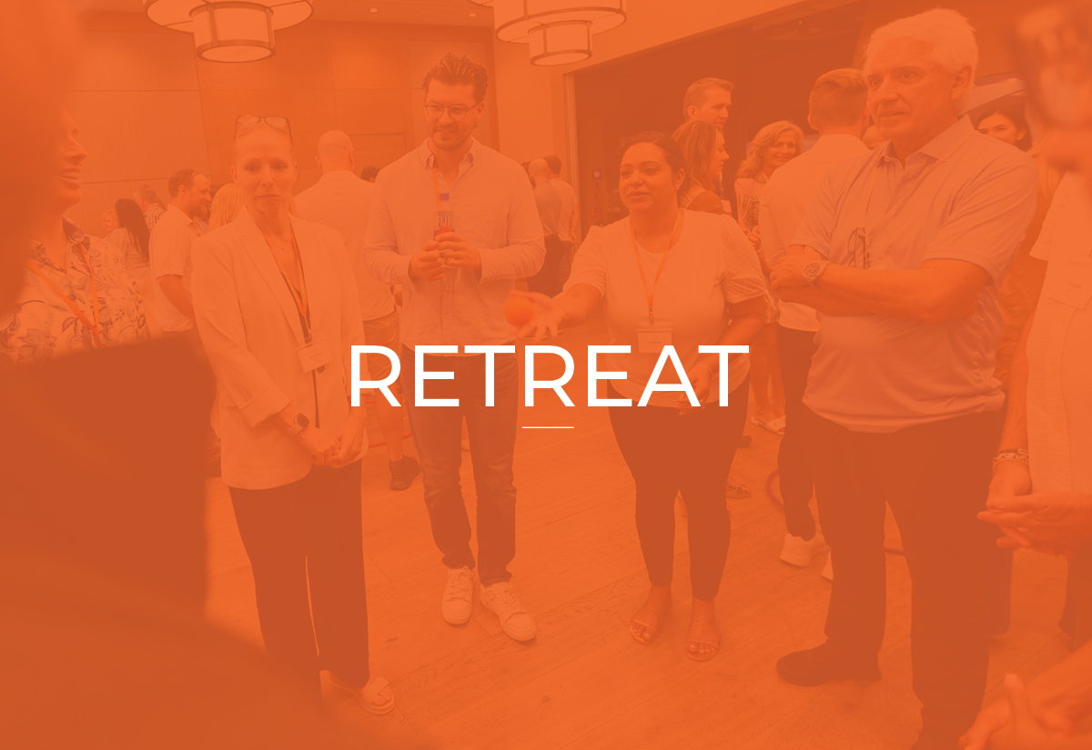 People gathering at a retreat event, engaging in conversation in a warmly lit indoor setting.