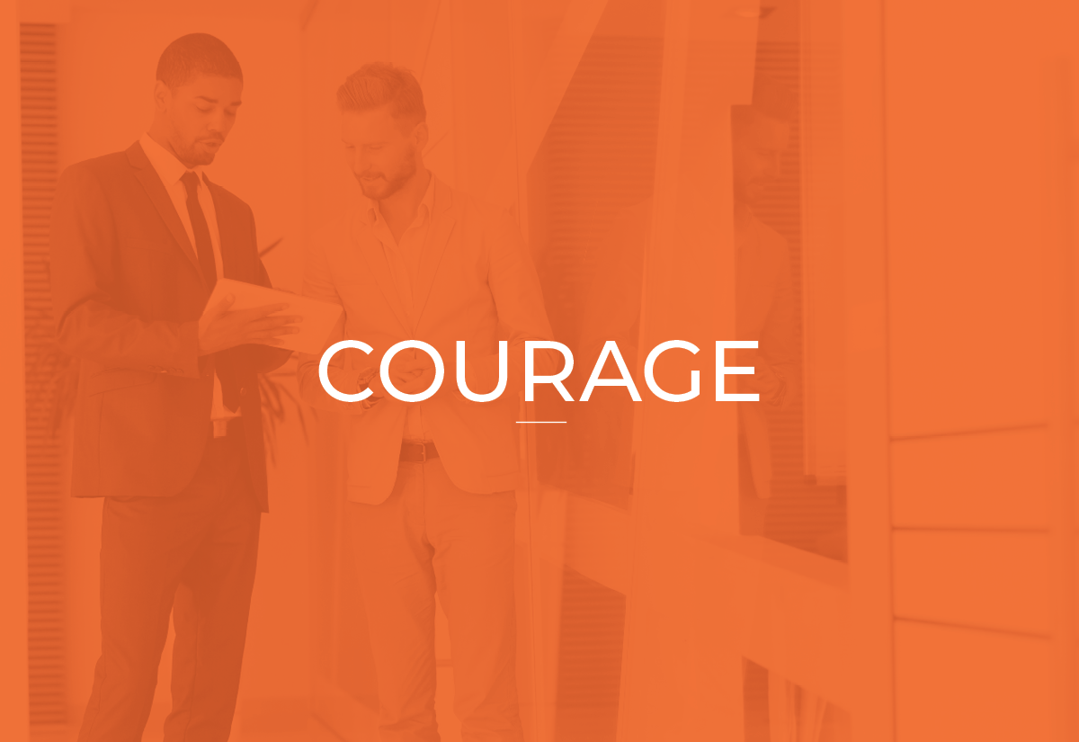 Two men in suits having a conversation in an office corridor with a large glass display case, overlaid with the word 'COURAGE' in white text.