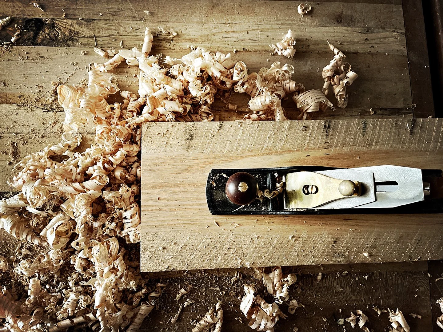 Hand plane shaving curls of wood on a workbench in the McLaughlin Woodworks shop, Baltimore.