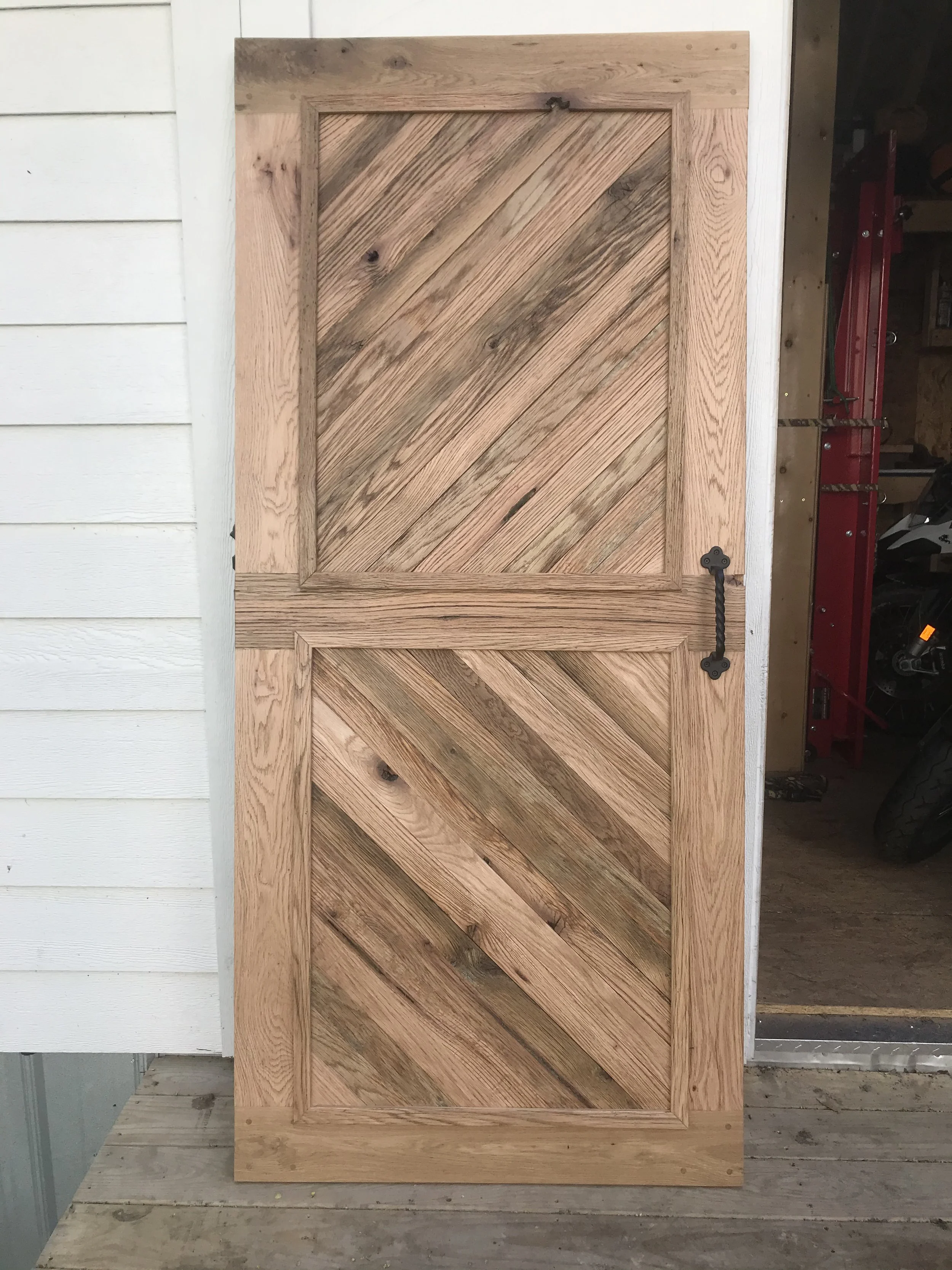 Custom oak Dutch door with diagonal herringbone paneling and wrought iron hardware, built in Baltimore.