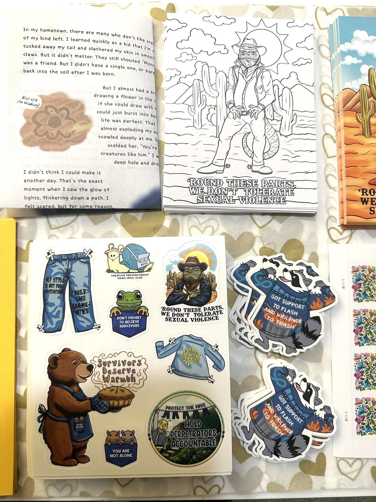 Collection of stickers, coloring book pages, and printed materials supporting survivors of sexual violence and promoting awareness. The stickers feature animals and messages such as 'Round these parts, we don't tolerate sexual violence' and 'Support survivors.'