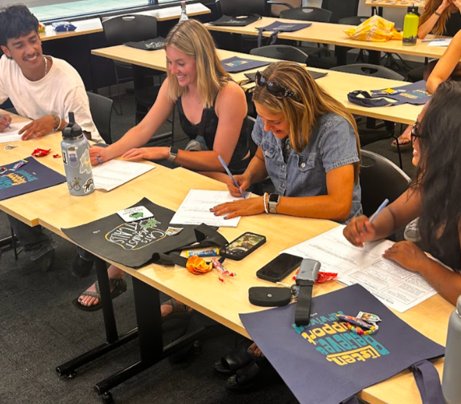 Group of four athletes sitting at a conference table, smiling and working on group activity during a workshop on sexual violence prevention
