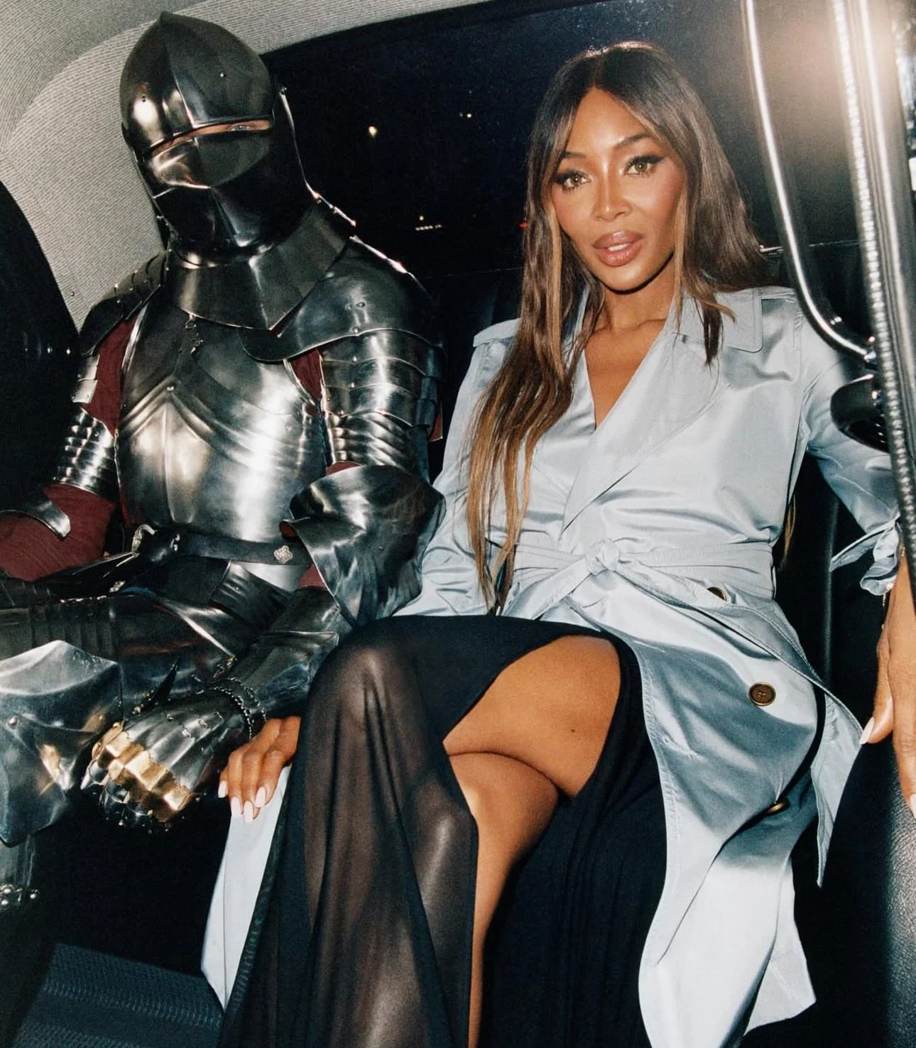 A woman sat in the back of a London cab, next to someone dressed as a knight in silver armour