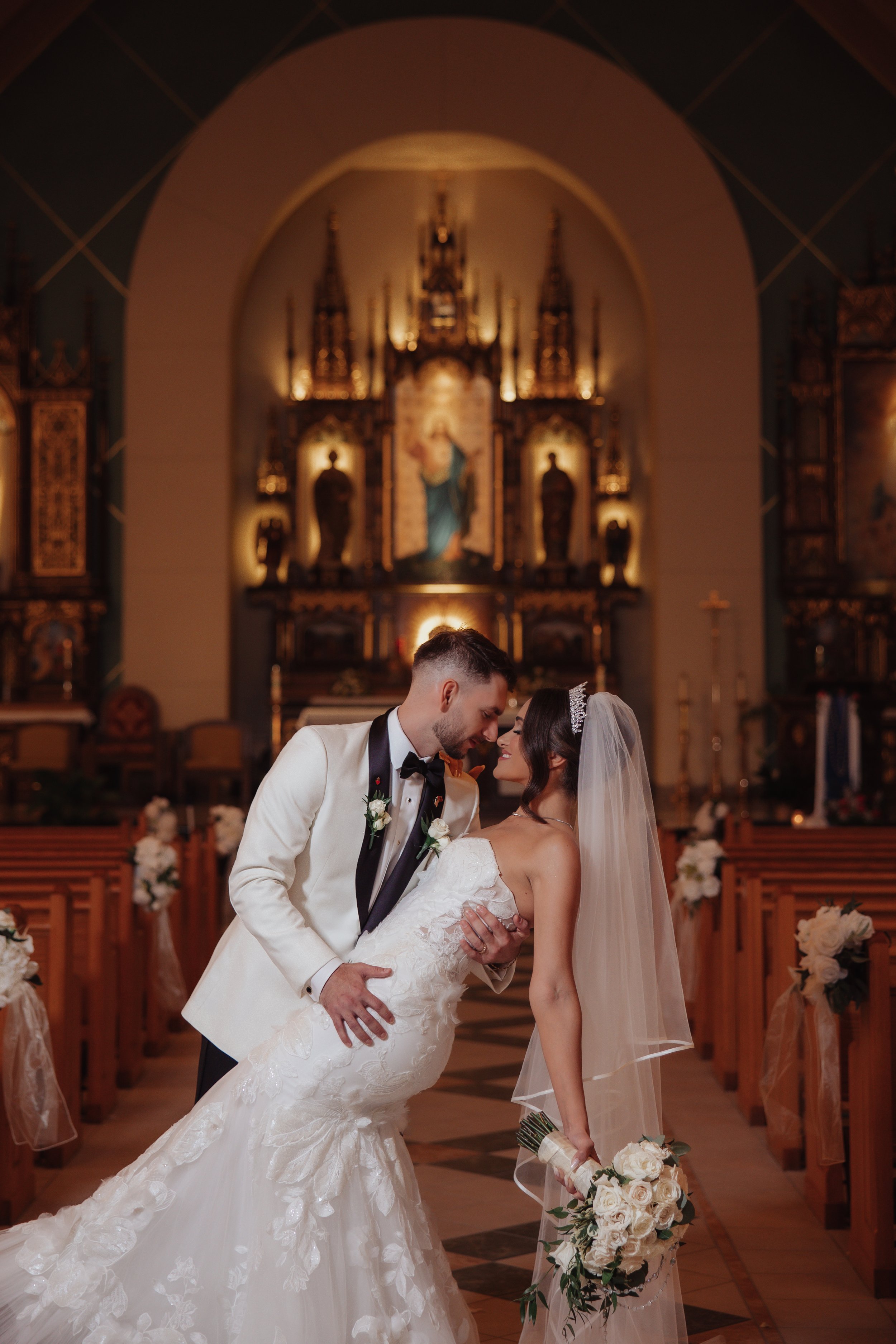 Bride and groom kissing in front of an ornate gold church altar