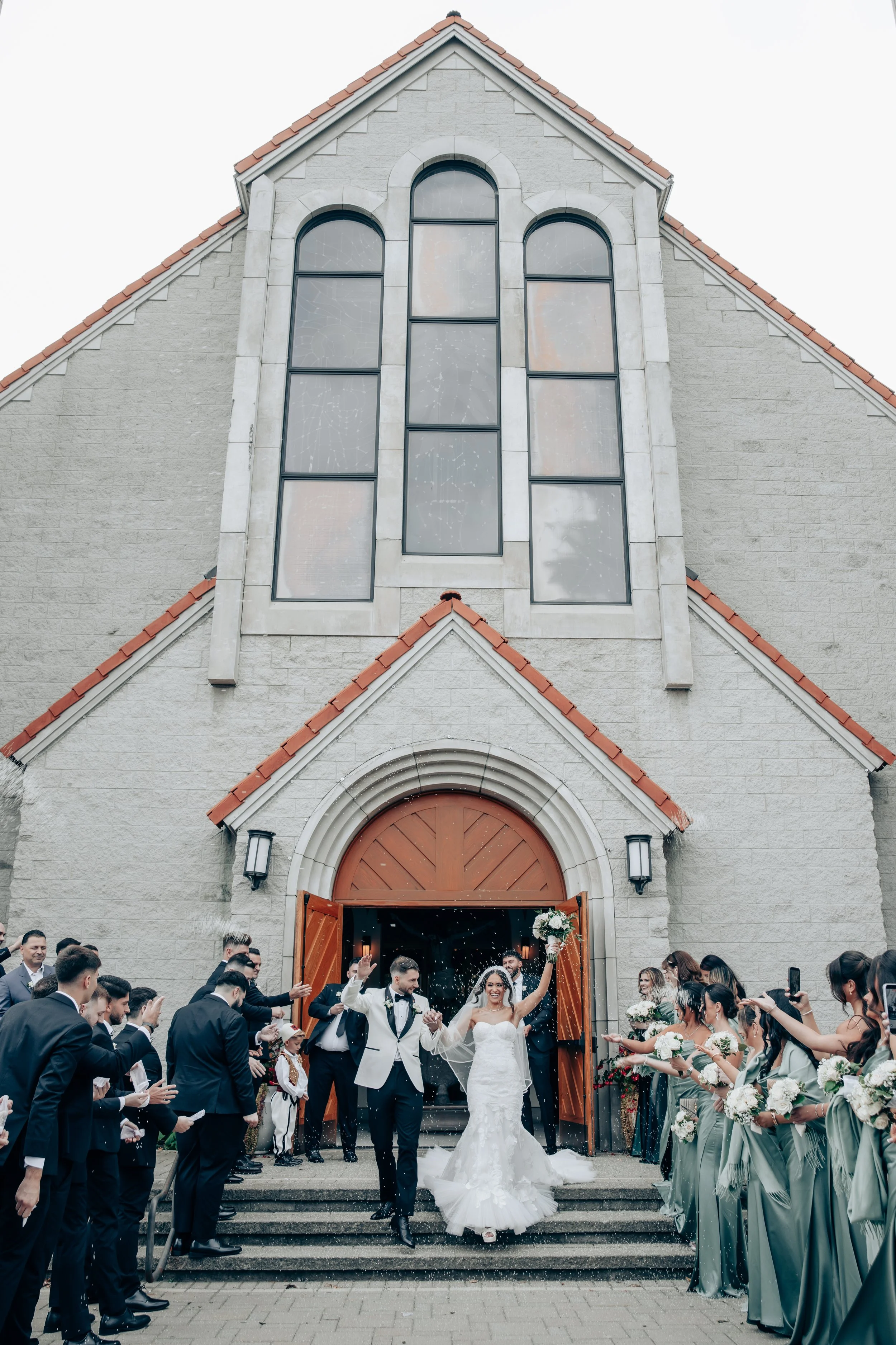Newlyweds leaving a stone church as guests cheer on the steps