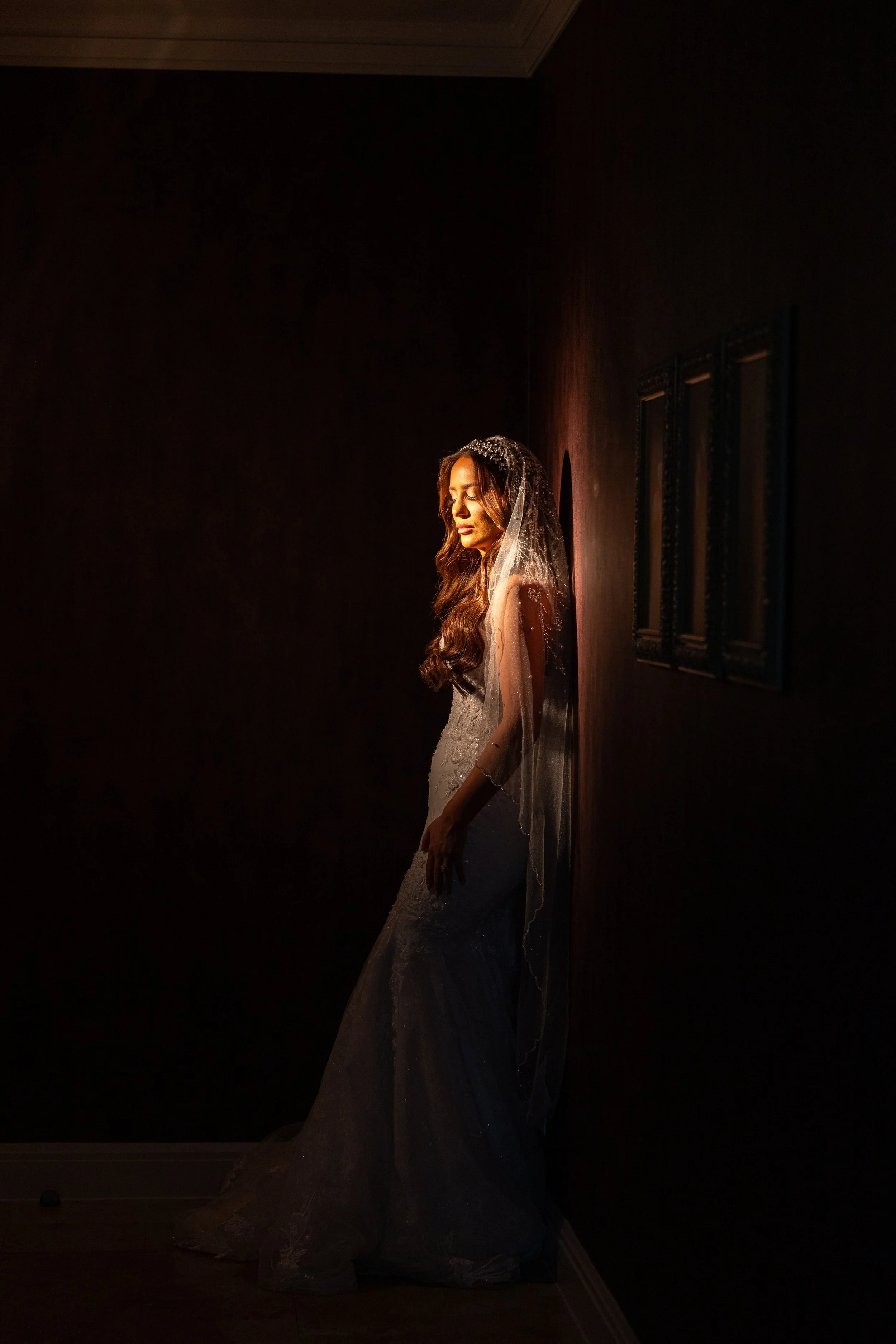 Bride standing in a soft beam of light in a dark room