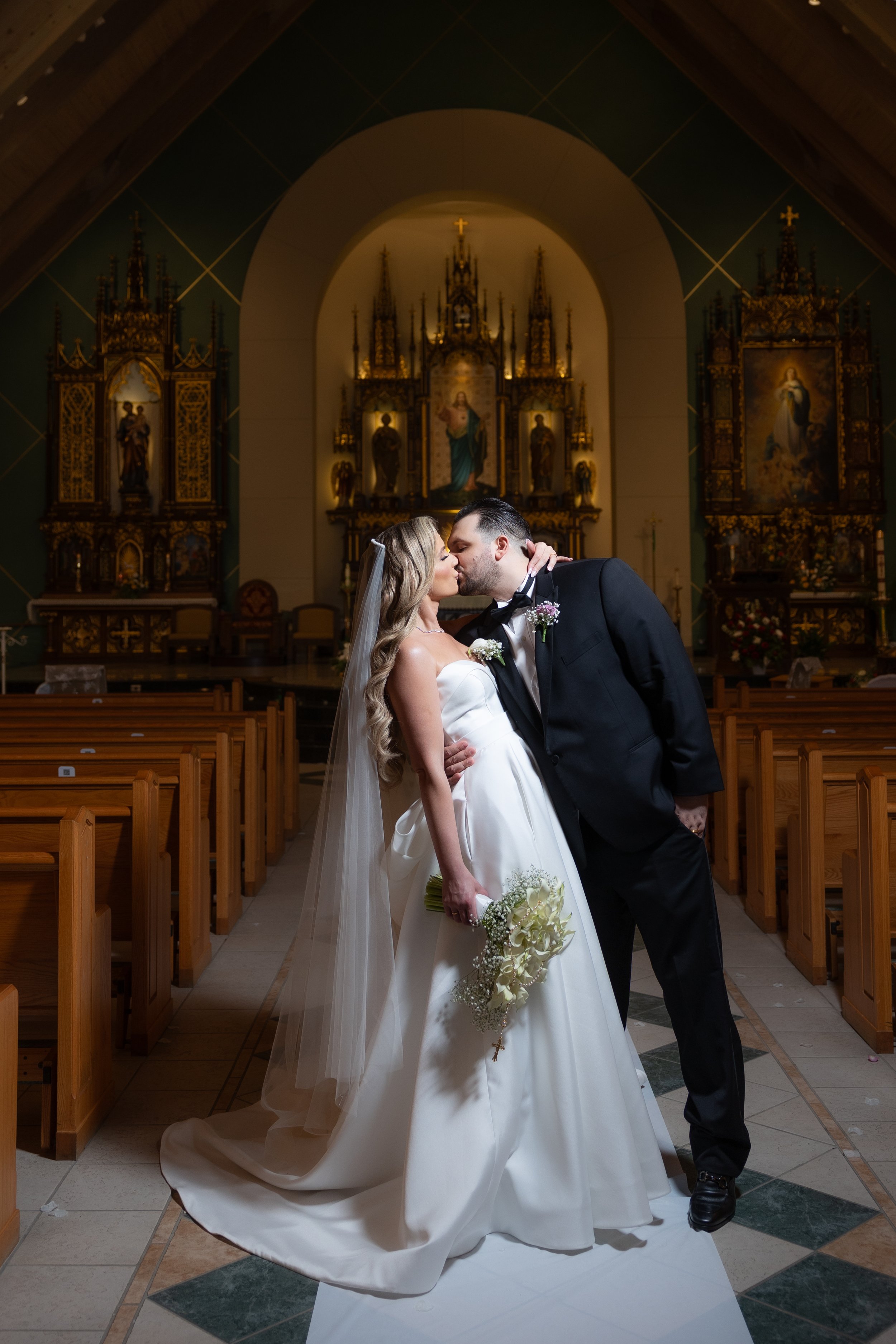 Bride and groom sharing a kiss in the aisle of a candlelit church