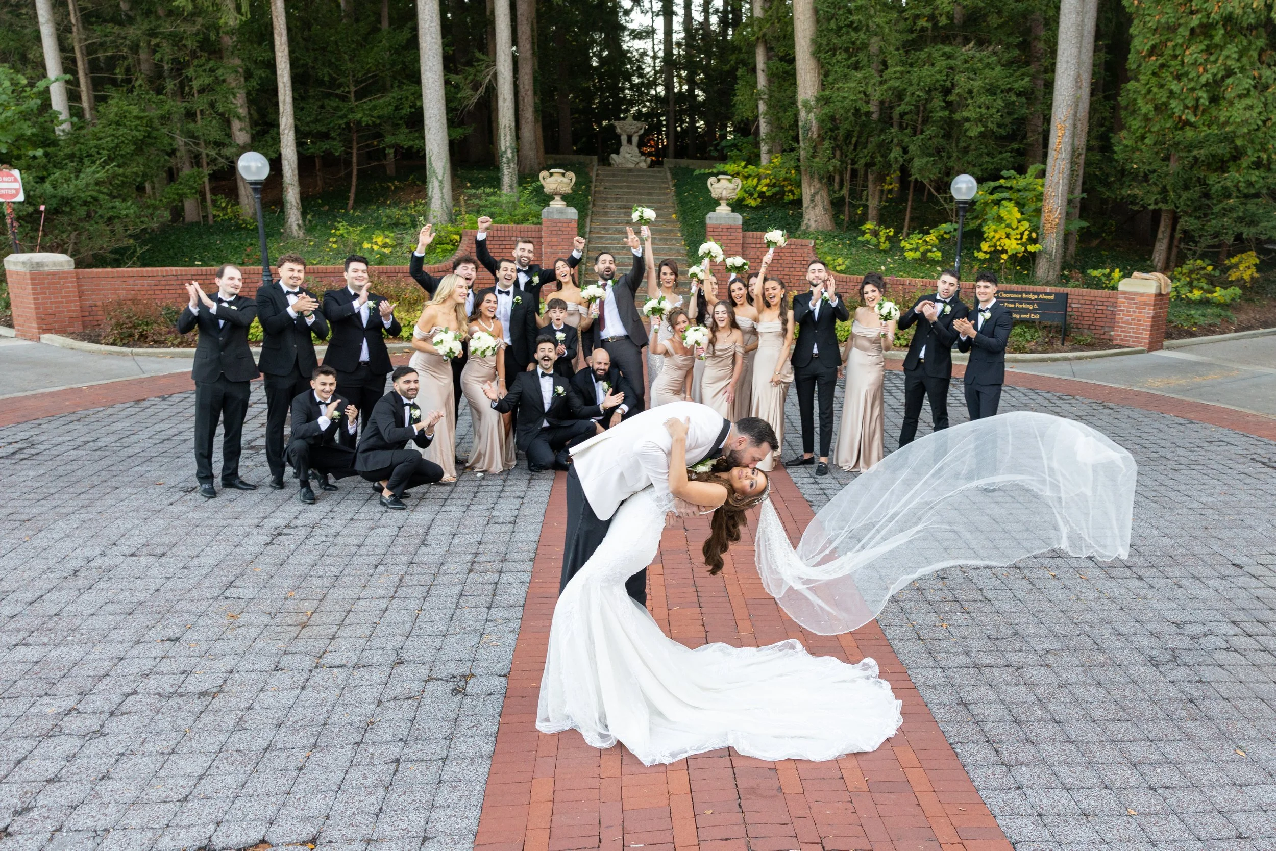 Groom dipping his bride in front of the cheering wedding party