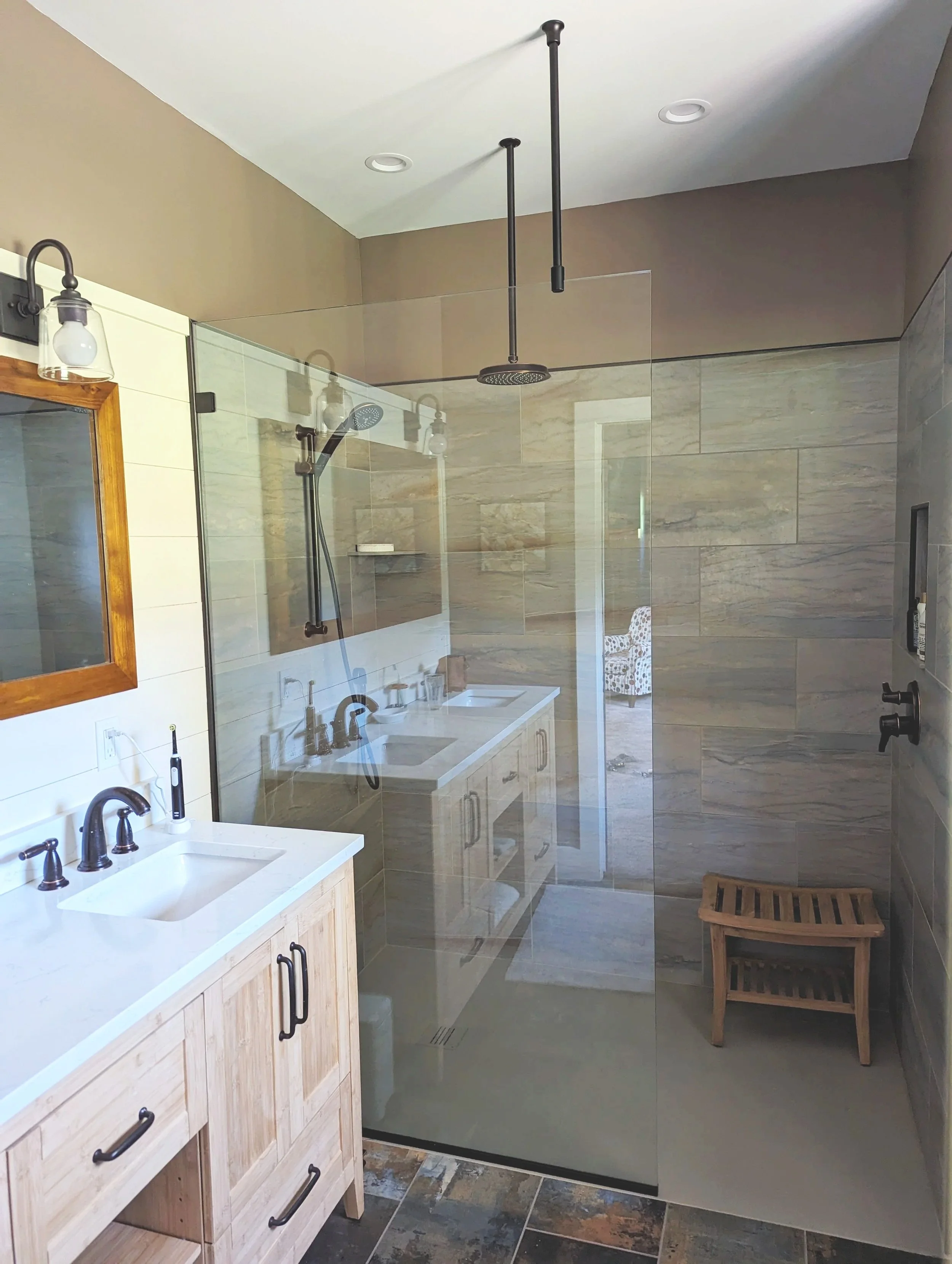 Modern bathroom with dual sinks, a large walk-in shower with glass enclosure, and rustic wood accents.