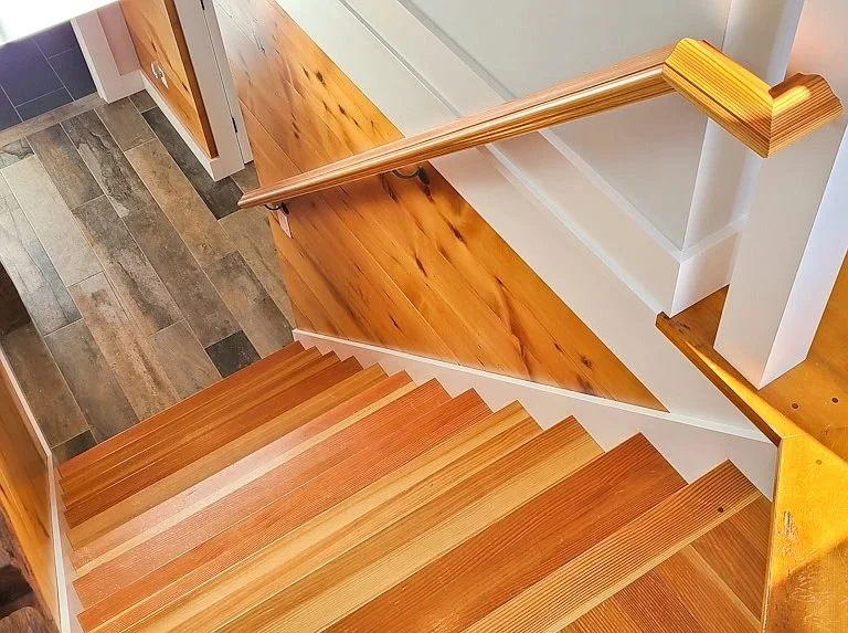 View of wooden staircase from the top, showing steps and handrails, with hardwood flooring at the bottom.