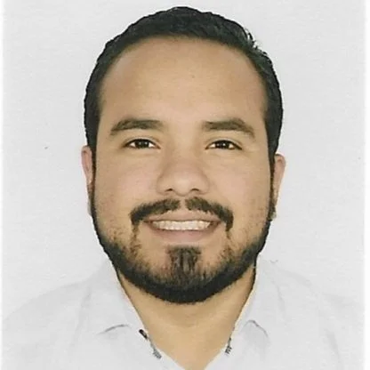 Retrato de un hombre con barba y bigote sonriendo, usando camisa blanca, fondo blanco.
