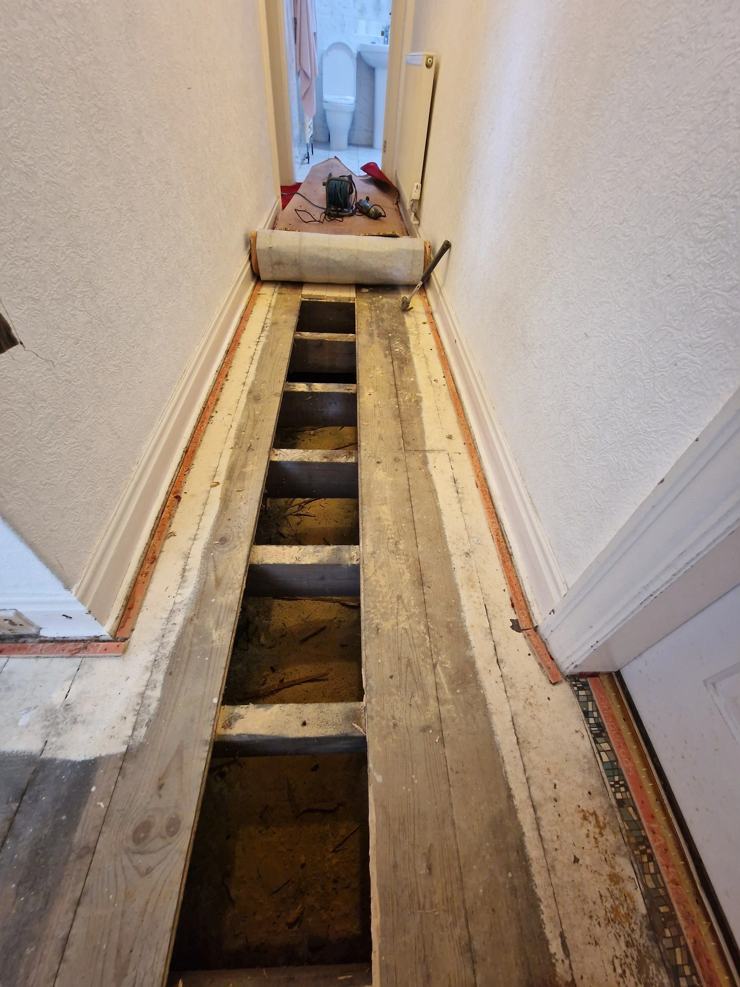 Rotten floorboards being replaced in a hallway