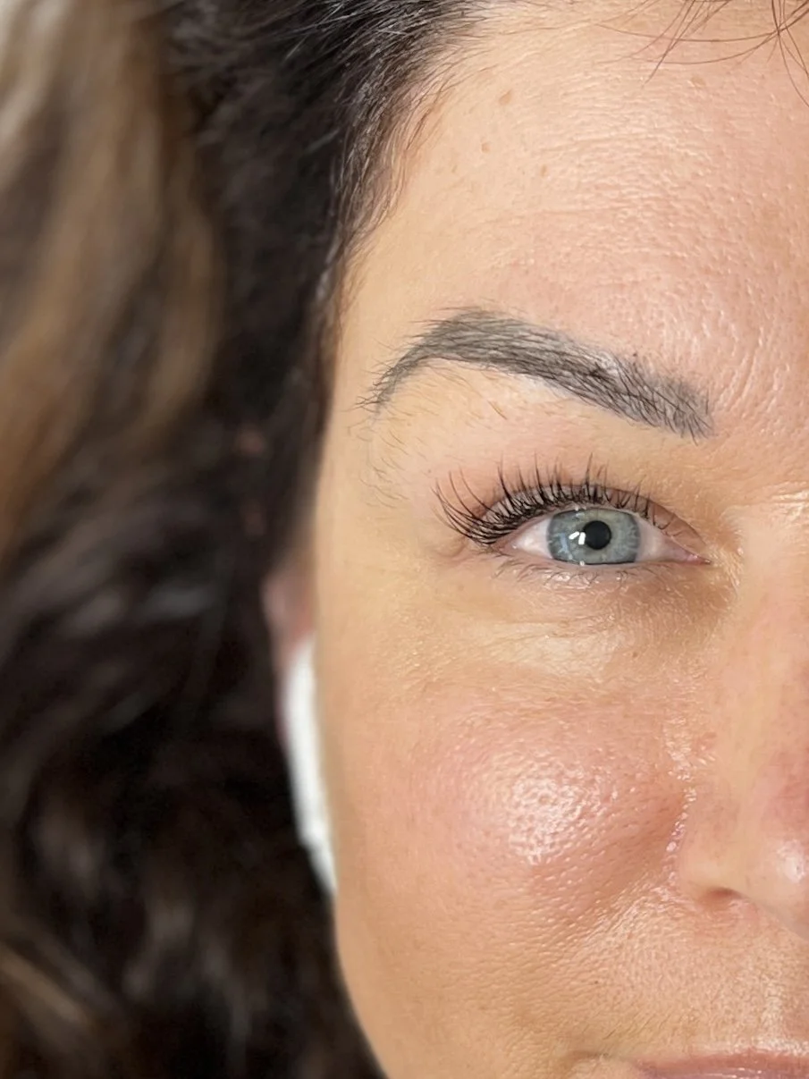 Close-up of a woman's face showing her eye, eyebrow, and part of her cheek with visible skin texture and makeup.