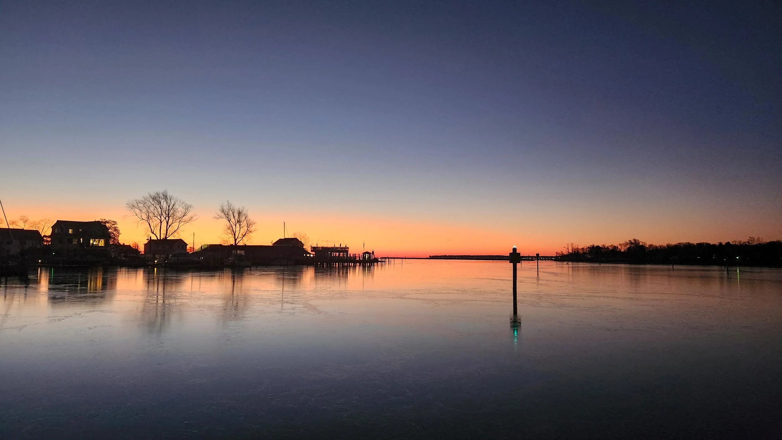 A slick sheet of ice covers the entrance to the harbor at sunrise
