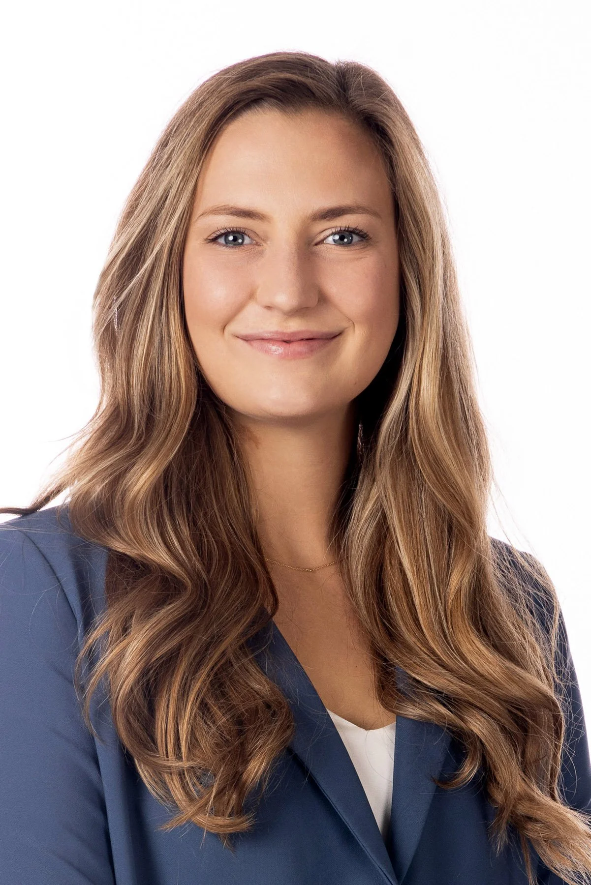 Professional portrait of a woman with long wavy light brown hair wearing a navy blazer and white top, smiling at the camera against a white background. Salt Lake City Portrait & Headshot Photographer - Nick Sokoloff - Utah