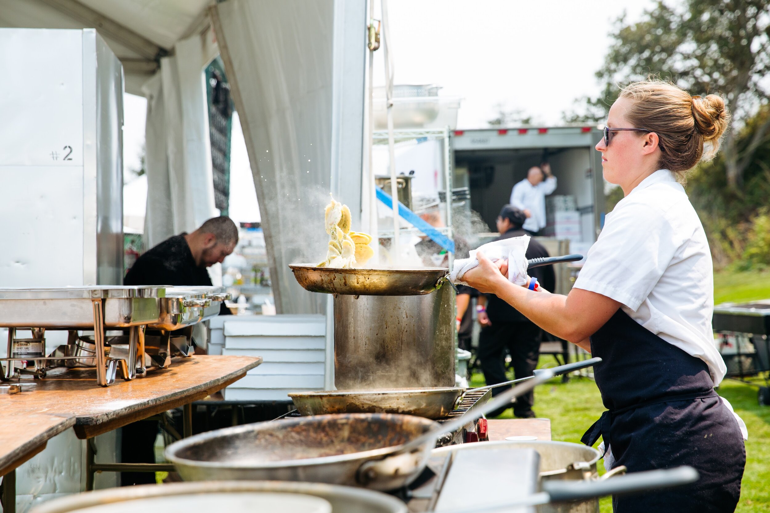  A Chef flambeing a dish outside at an event 