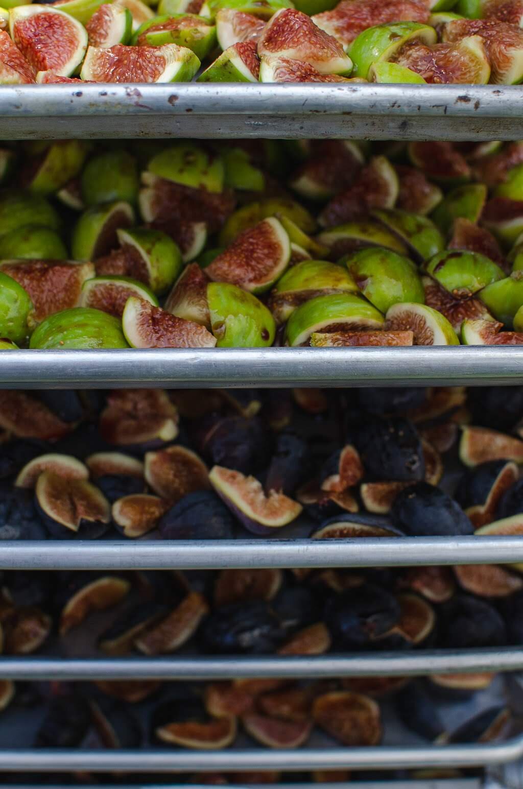  Fresh halved black and green figs on sheet trays on a speedrack 
