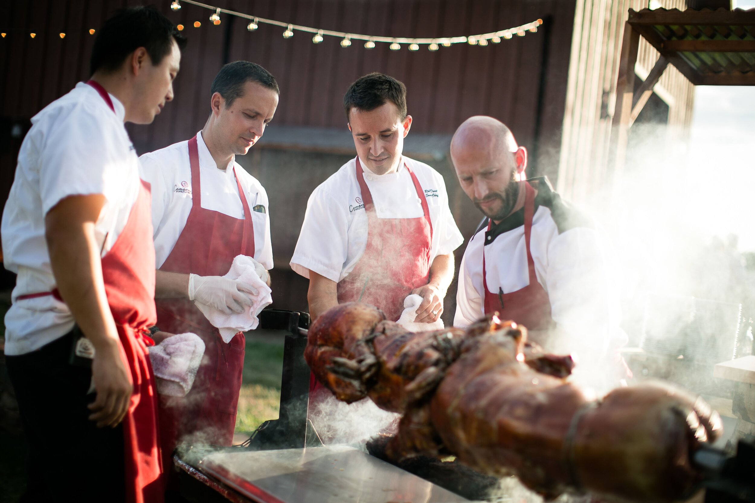  Chefs spit roasting a whole pig over an open fire 