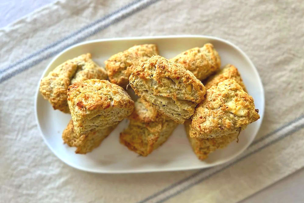 flat lay photograph of herby cheddar biscuits piled onto a round oval white plate