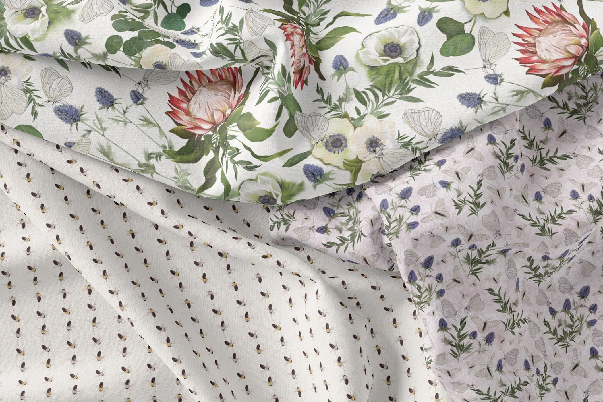 Four fabric towels with floral and butterfly patterns hanging side by side on a wall.