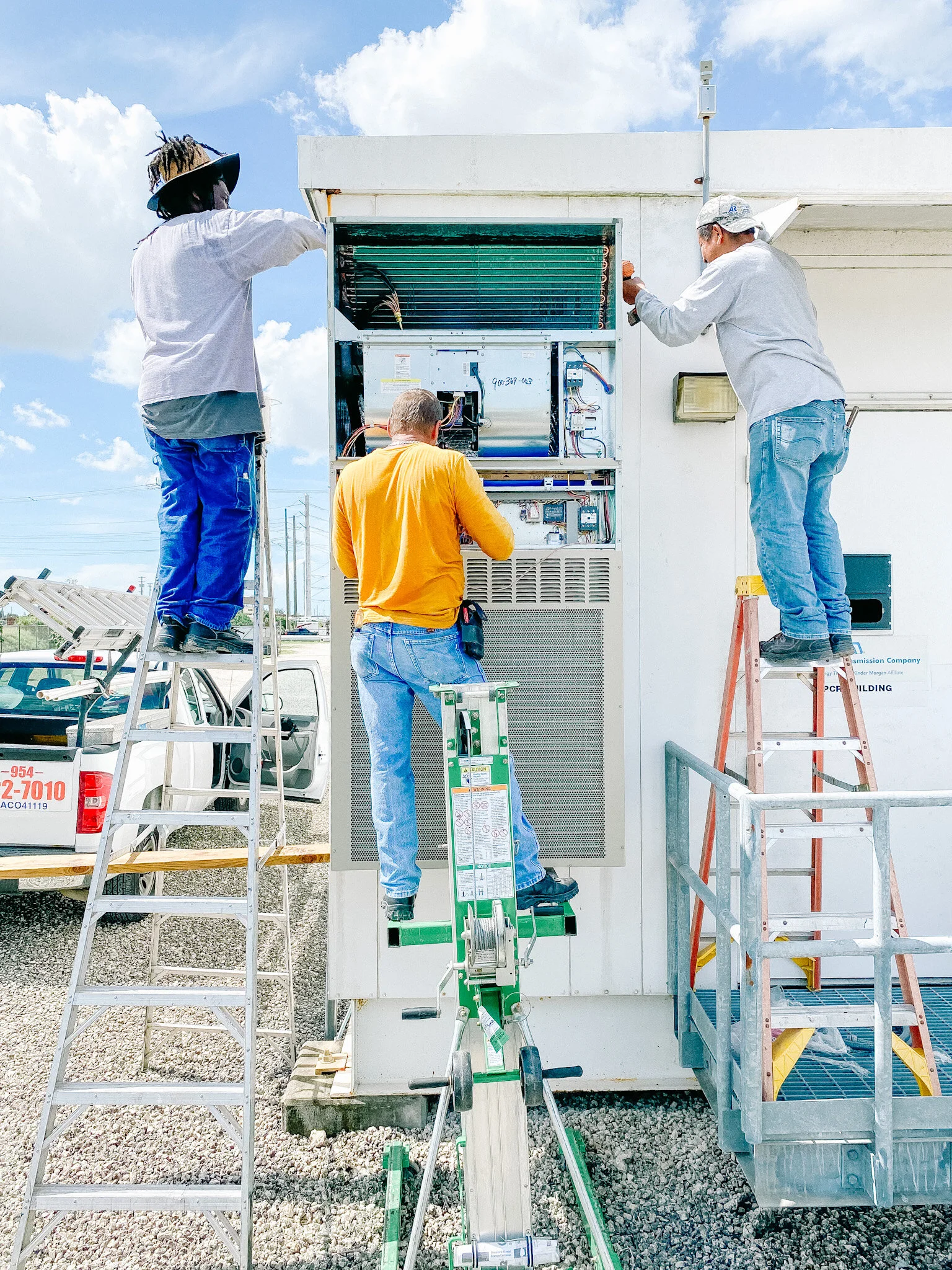 HVAC technicians installing and servicing an air conditioning unit at a South Florida property