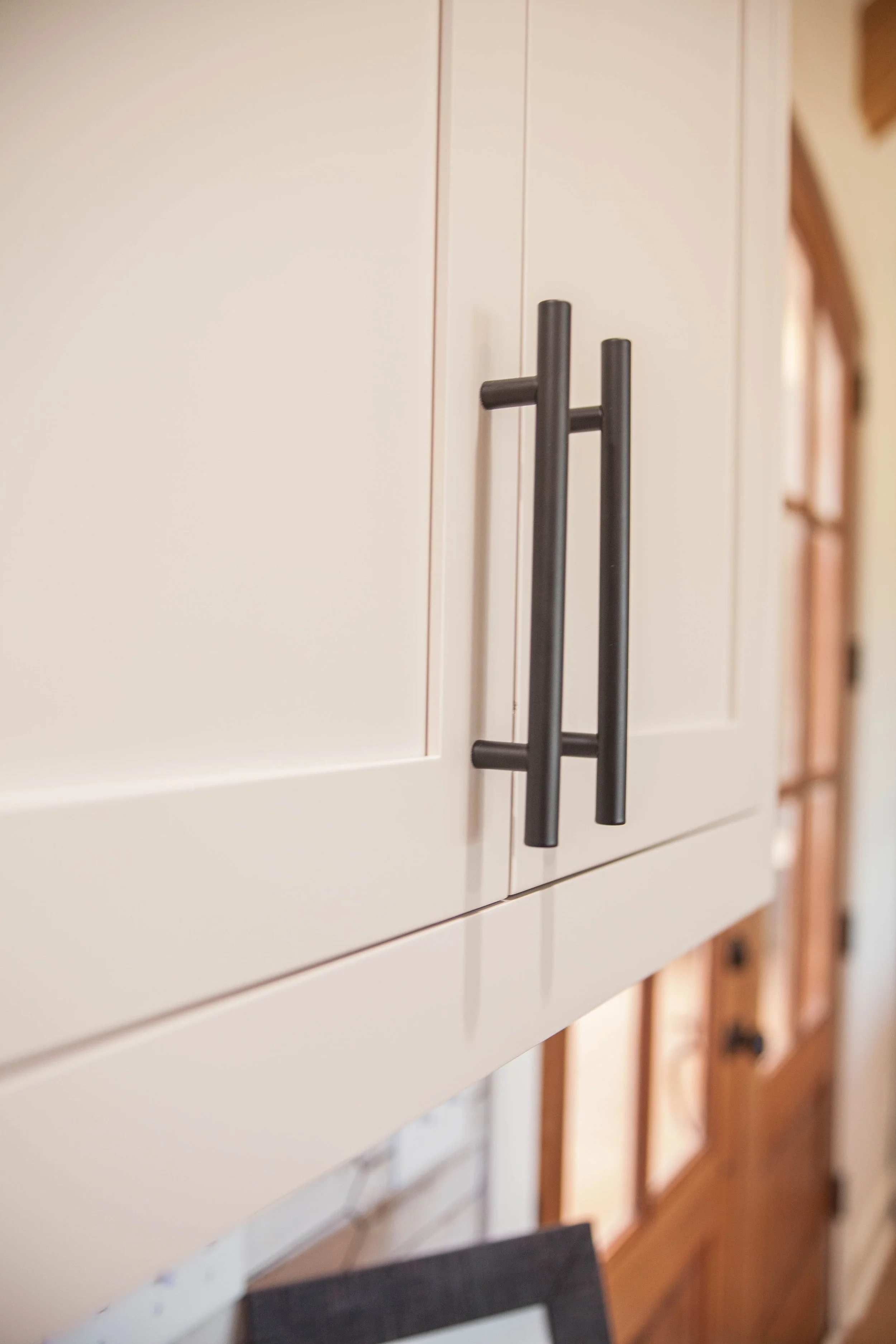 Close-up of a white kitchen cabinet with black handles. 