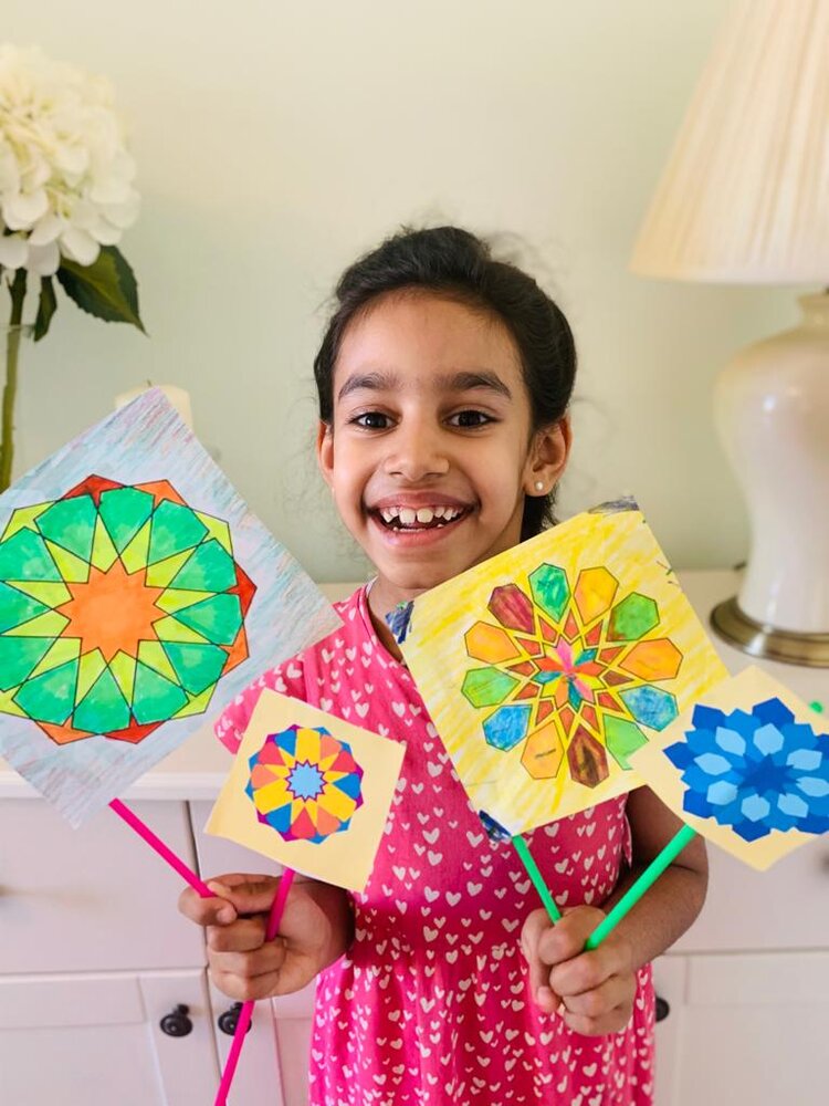 Girl holding flags made from EID colouring sheet patterns