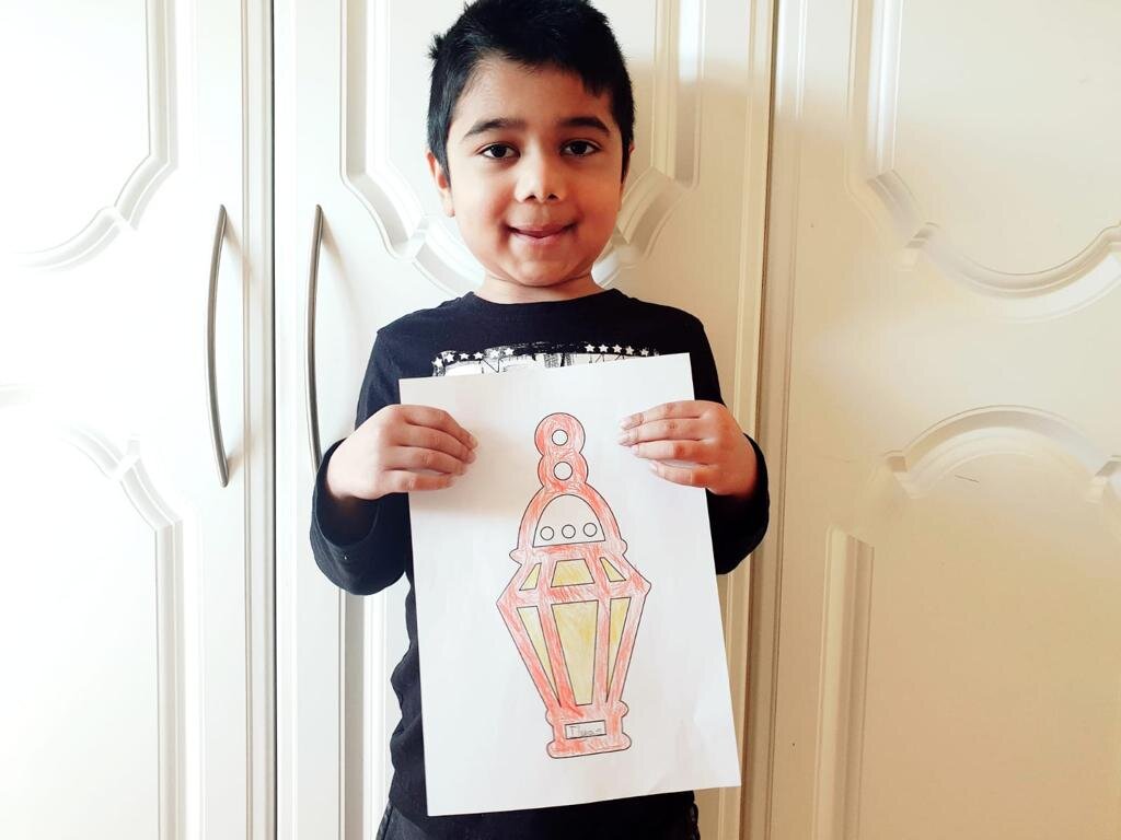 Boy holds EID colouring sheet of a lantern coloured in
