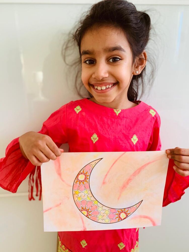 Girl holding picture made from EID colouring sheet crescent moon outline